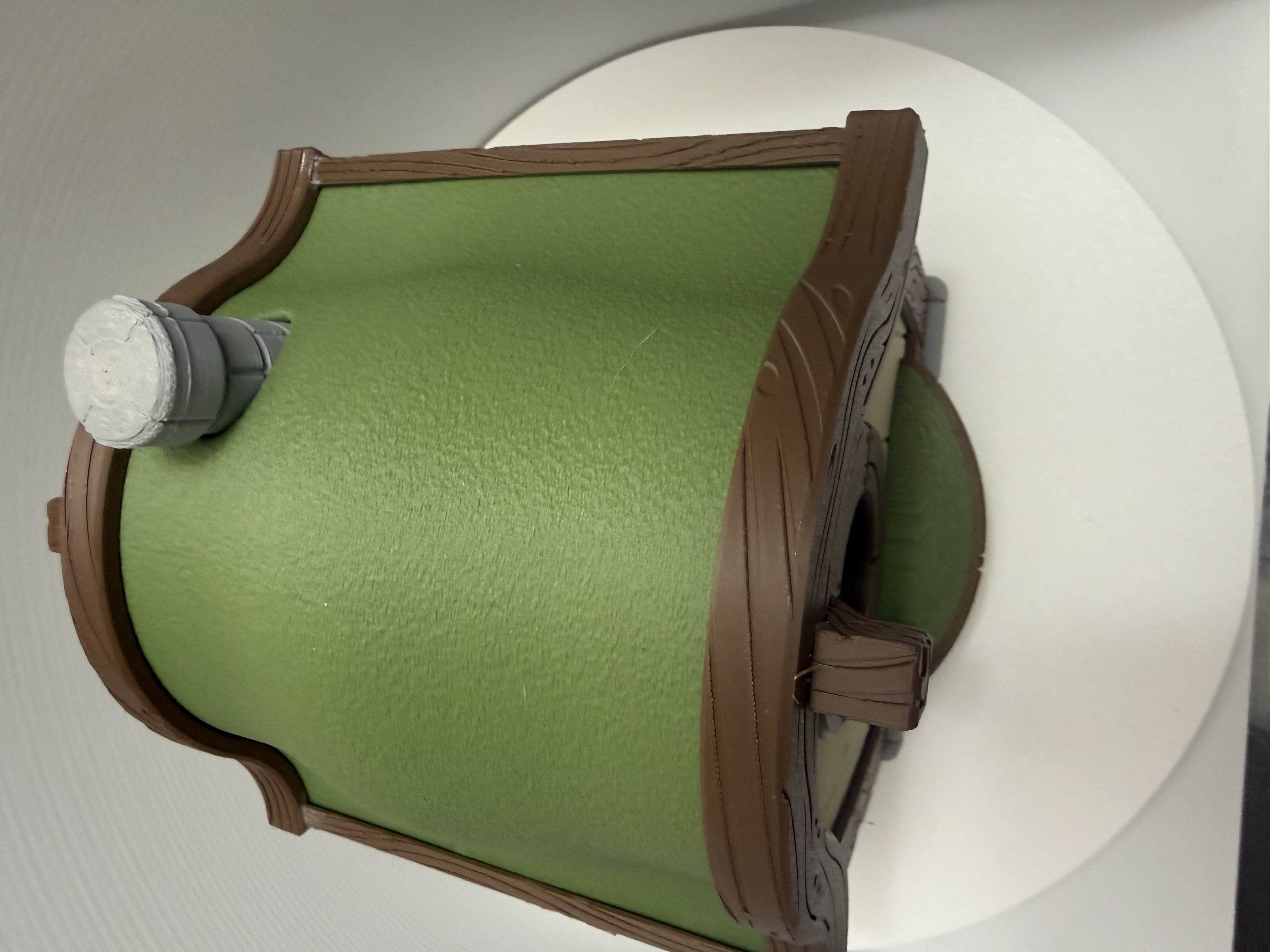 Top-down view of green textured cottage roof with grey chimney and carved brown trim
