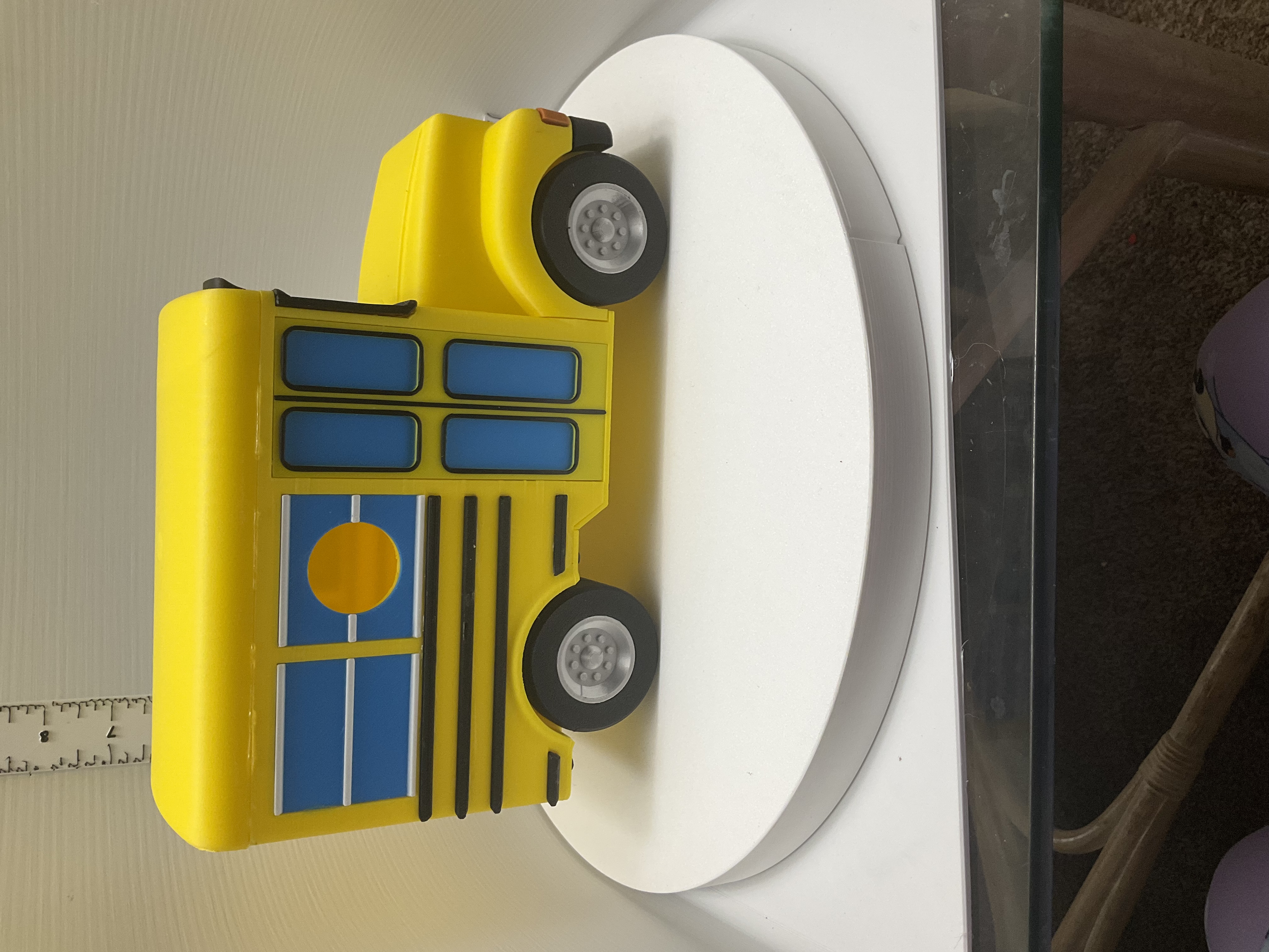 Side view of yellow school bus birdhouse with blue windows and round entry hole