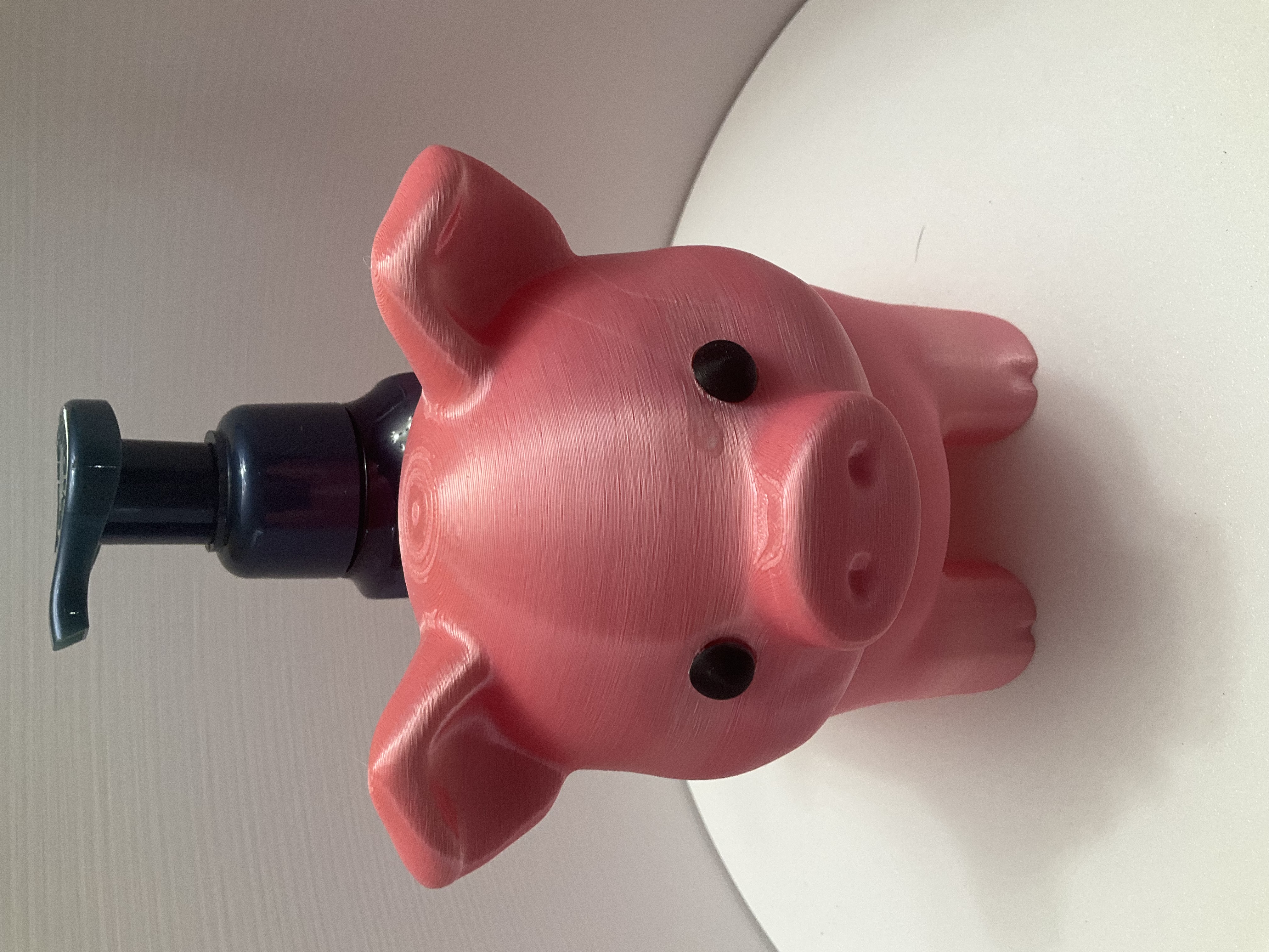 Front view of pink pig soap dispenser holder with pump bottle inserted through back