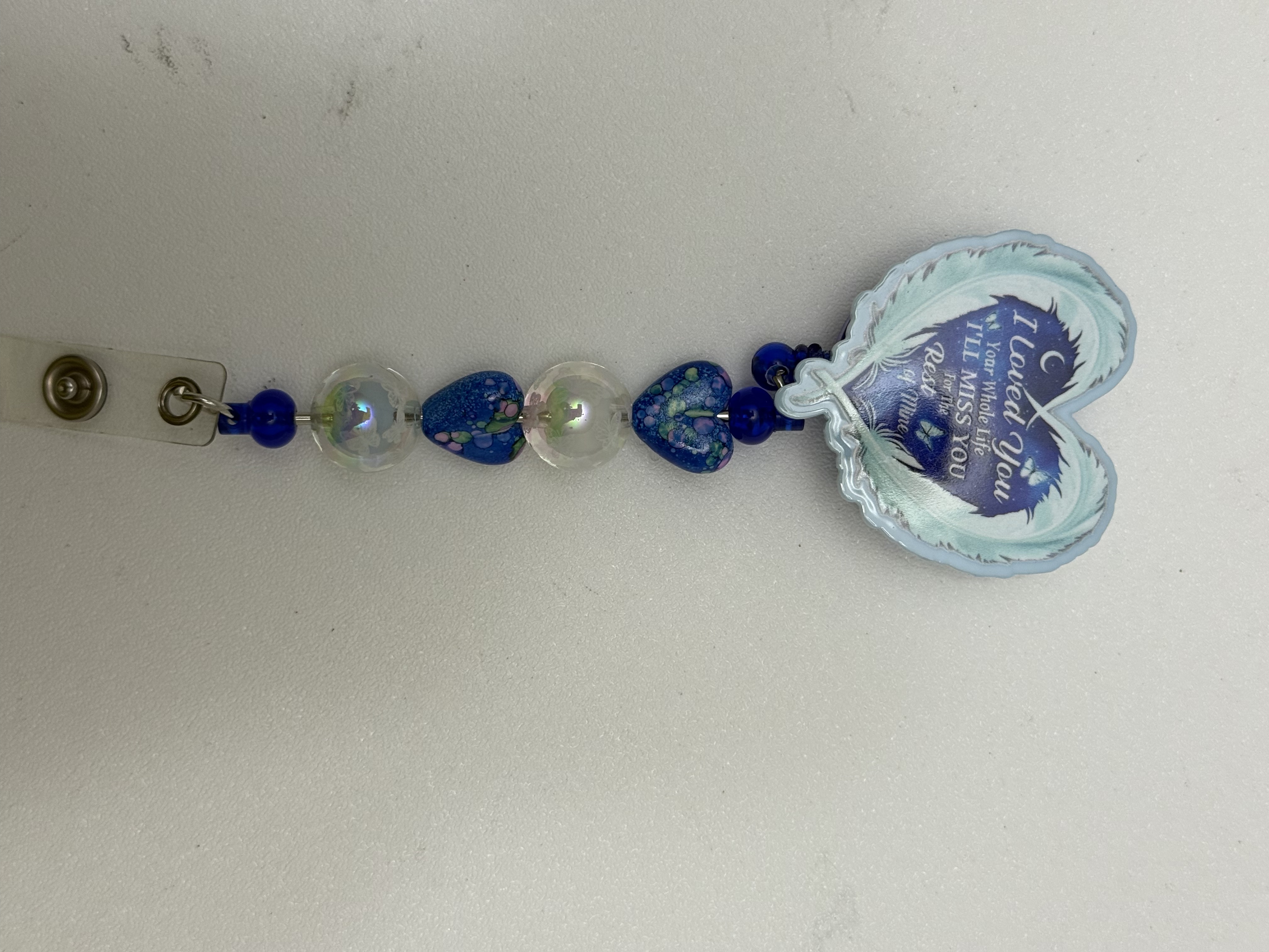 Beaded badge reel with cobalt blue hearts, iridescent beads, and a pale blue memorial heart charm reading I Loved You Your Whole Life
