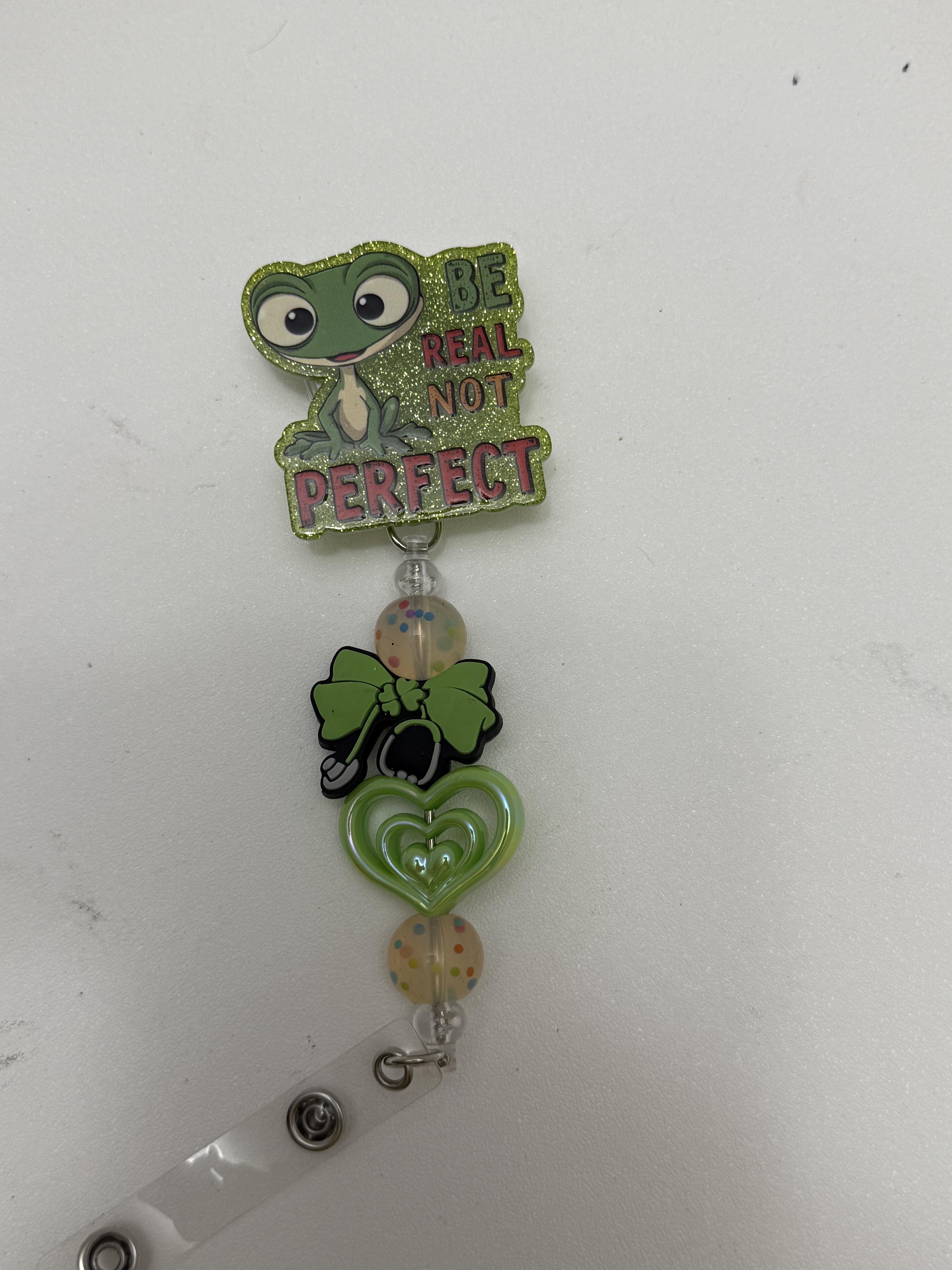 Glitter frog badge reel with bow charm, green heart, and confetti beads on retractable clip