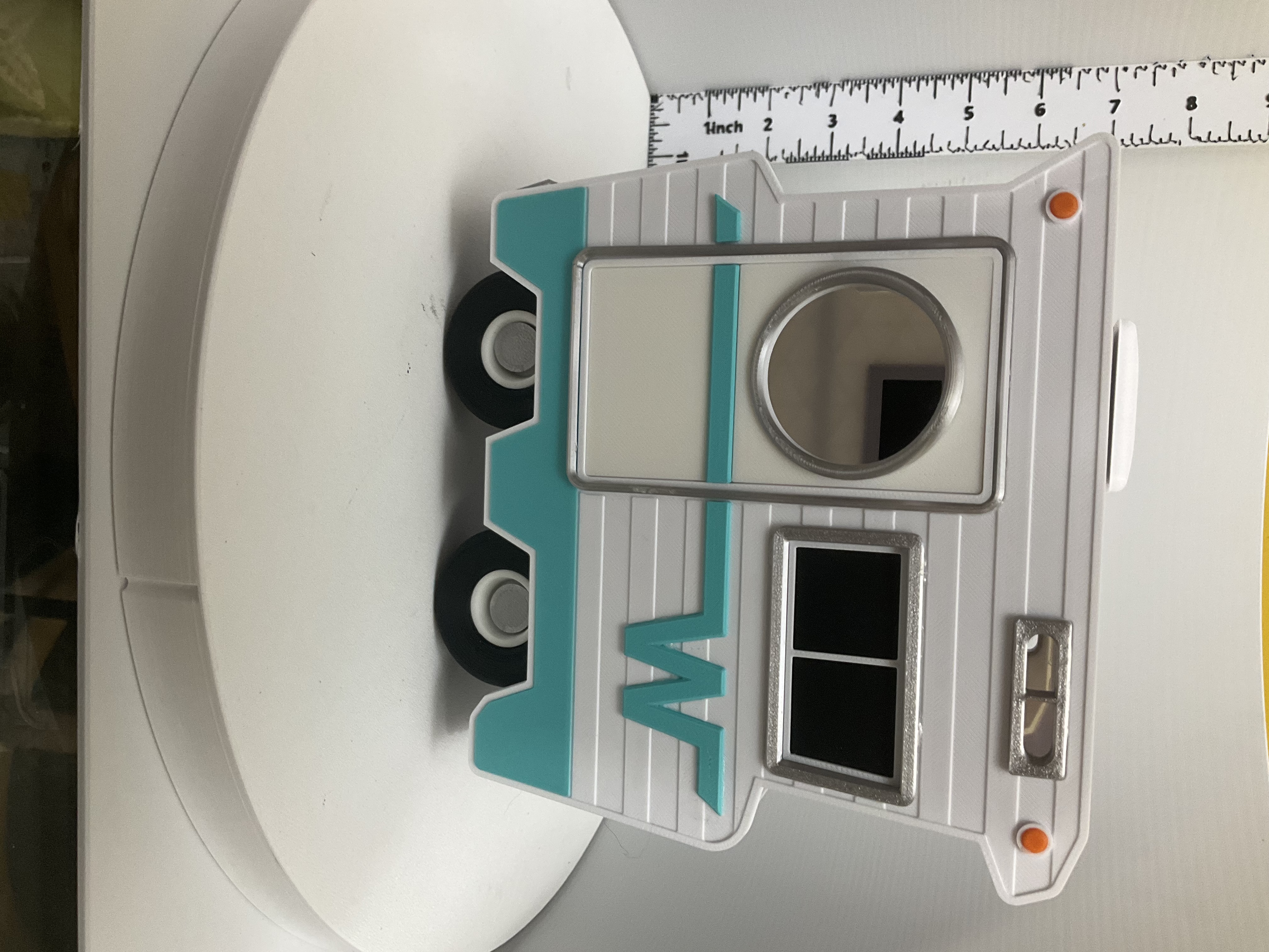 Side view of white and teal retro camper birdhouse with round entry hole and orange accent dots
