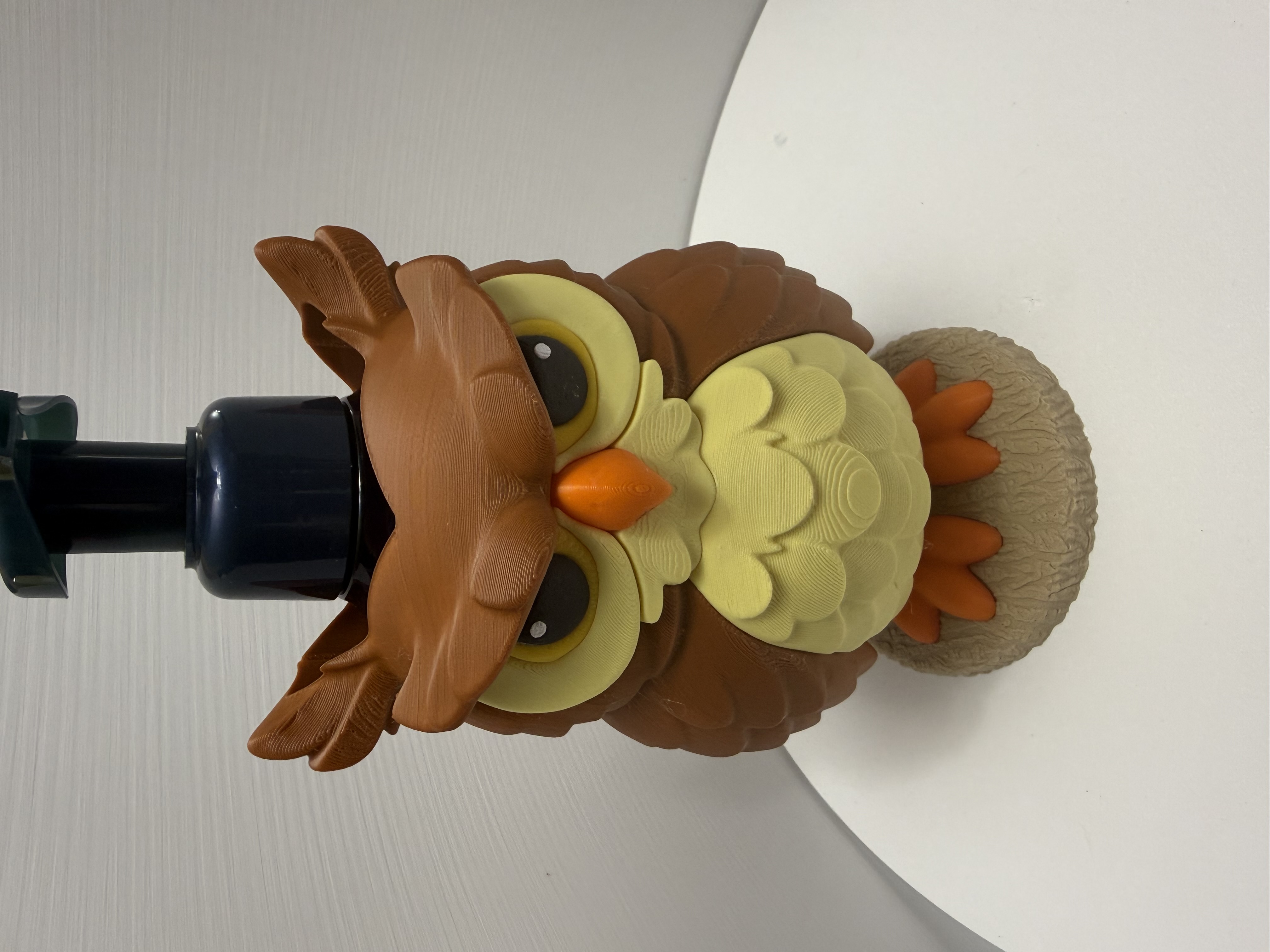Front view of grumpy owl soap dispenser with brown feathers, yellow chest, and orange beak