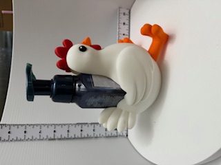 White chicken soap holder with red comb and orange feet cradling a dark foam pump bottle, side view