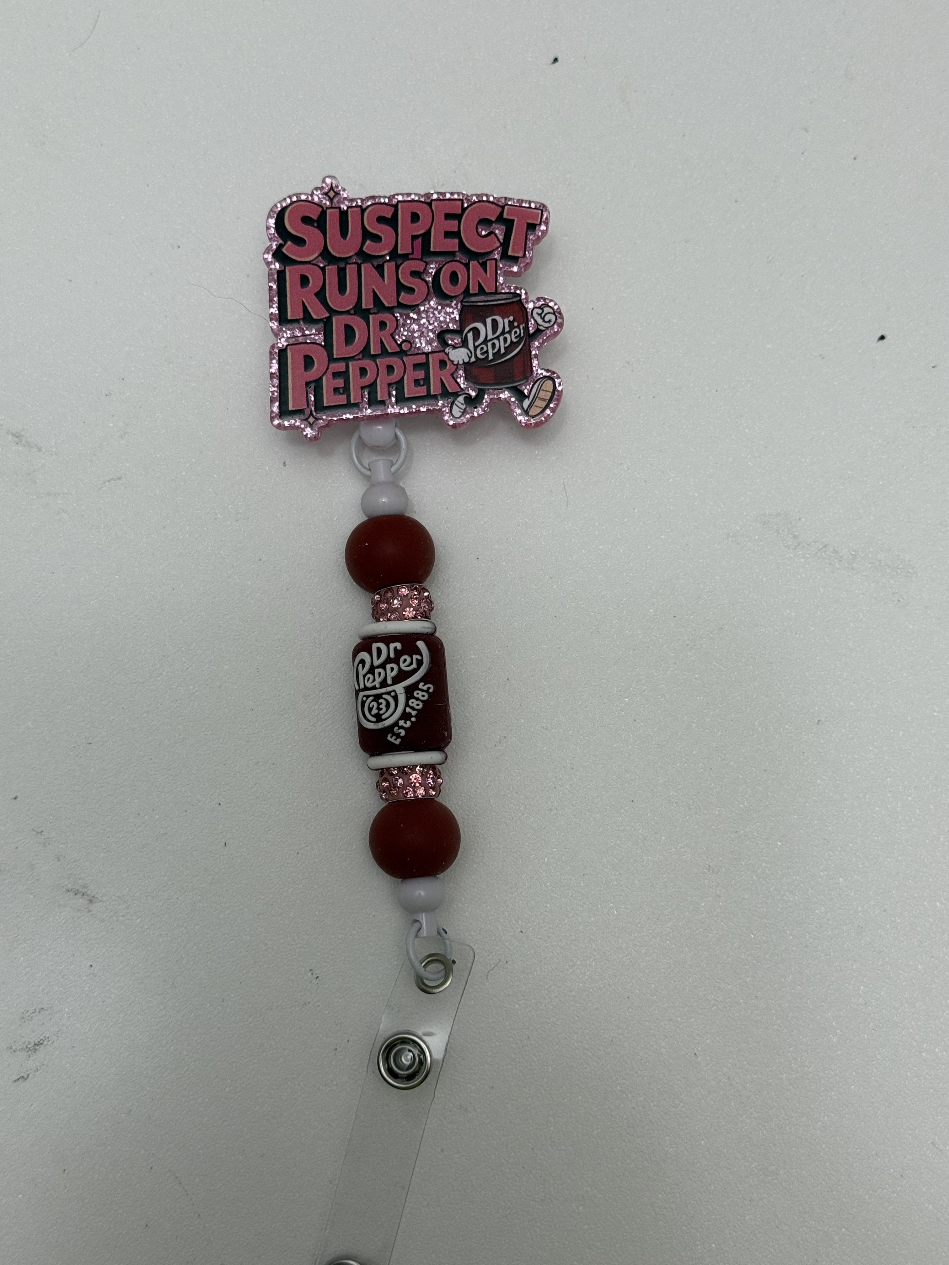 Retractable badge reel with glittery pink soda-lover topper and dark burgundy beads