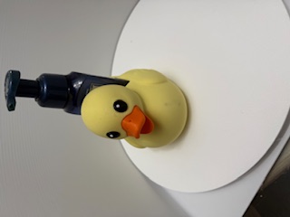Yellow duck-shaped holder with black foam pump bottle inserted in its back, front view