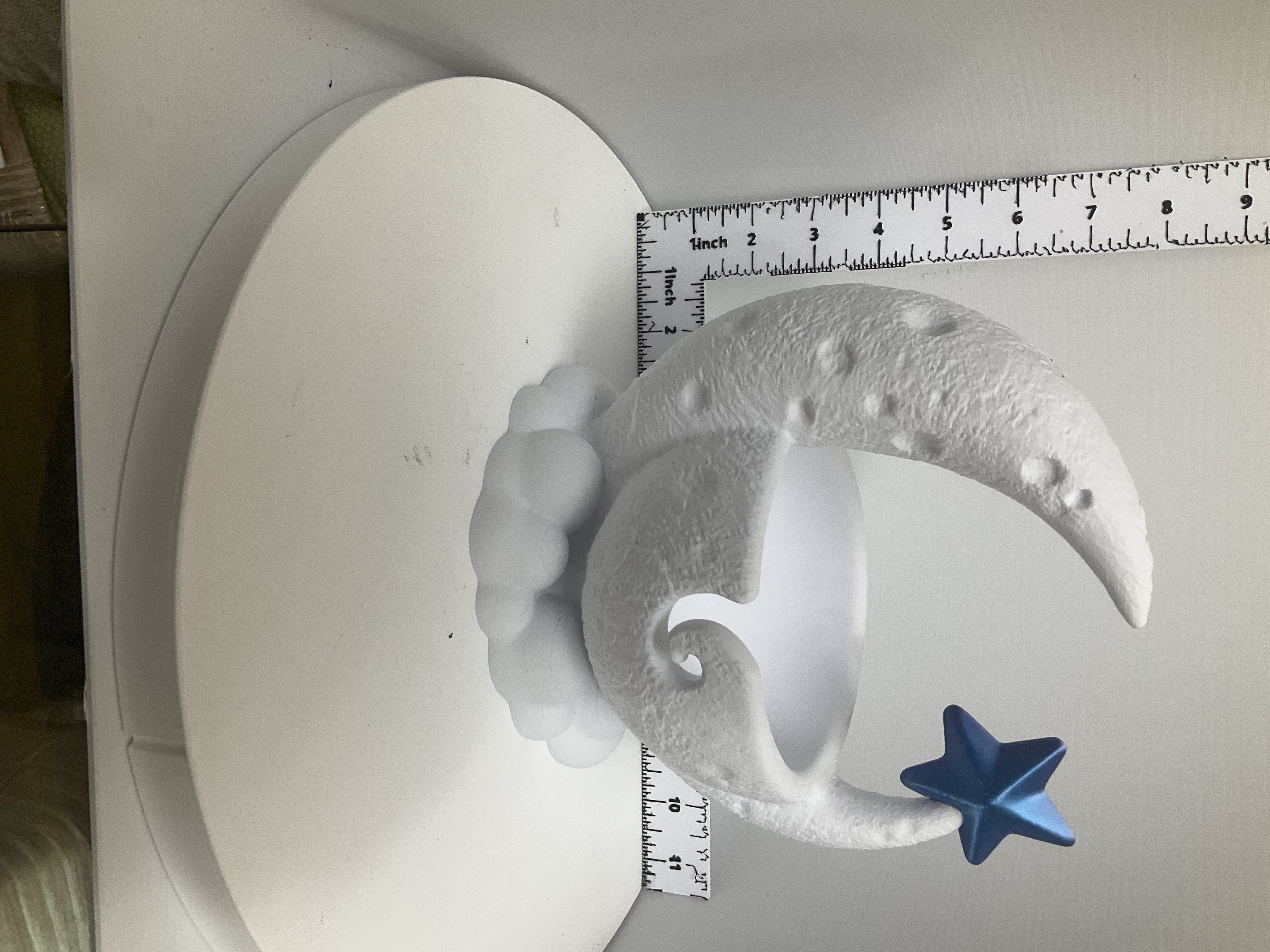 White crescent moon yarn bowl on cloud base with blue star accent, shown beside ruler for scale