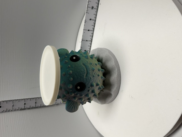 Teal 3D printed pufferfish candle holder with spines and wide eyes on sandy base