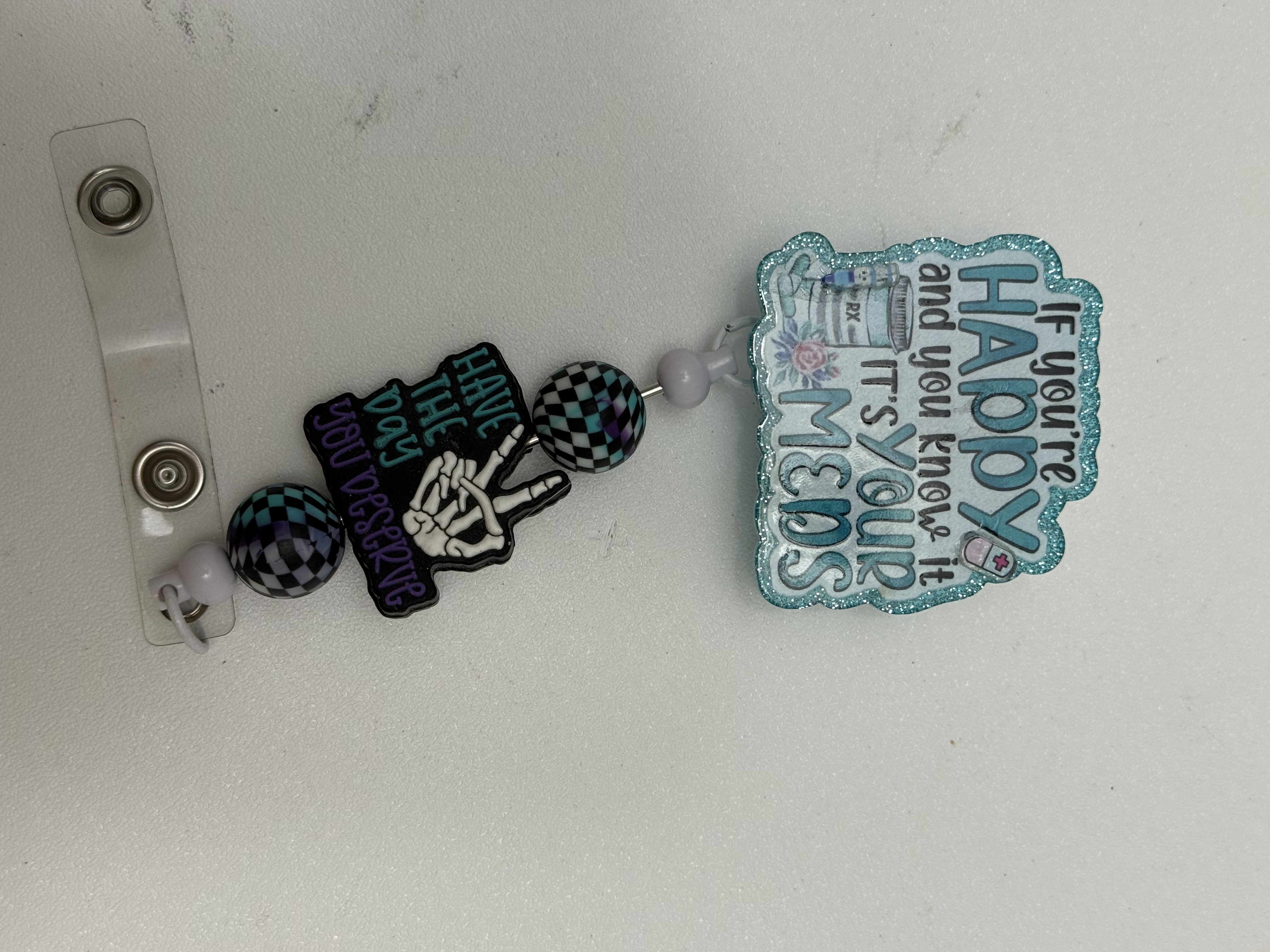 Two pharmacy badge reels side by side showing skeleton and glitter frame styles