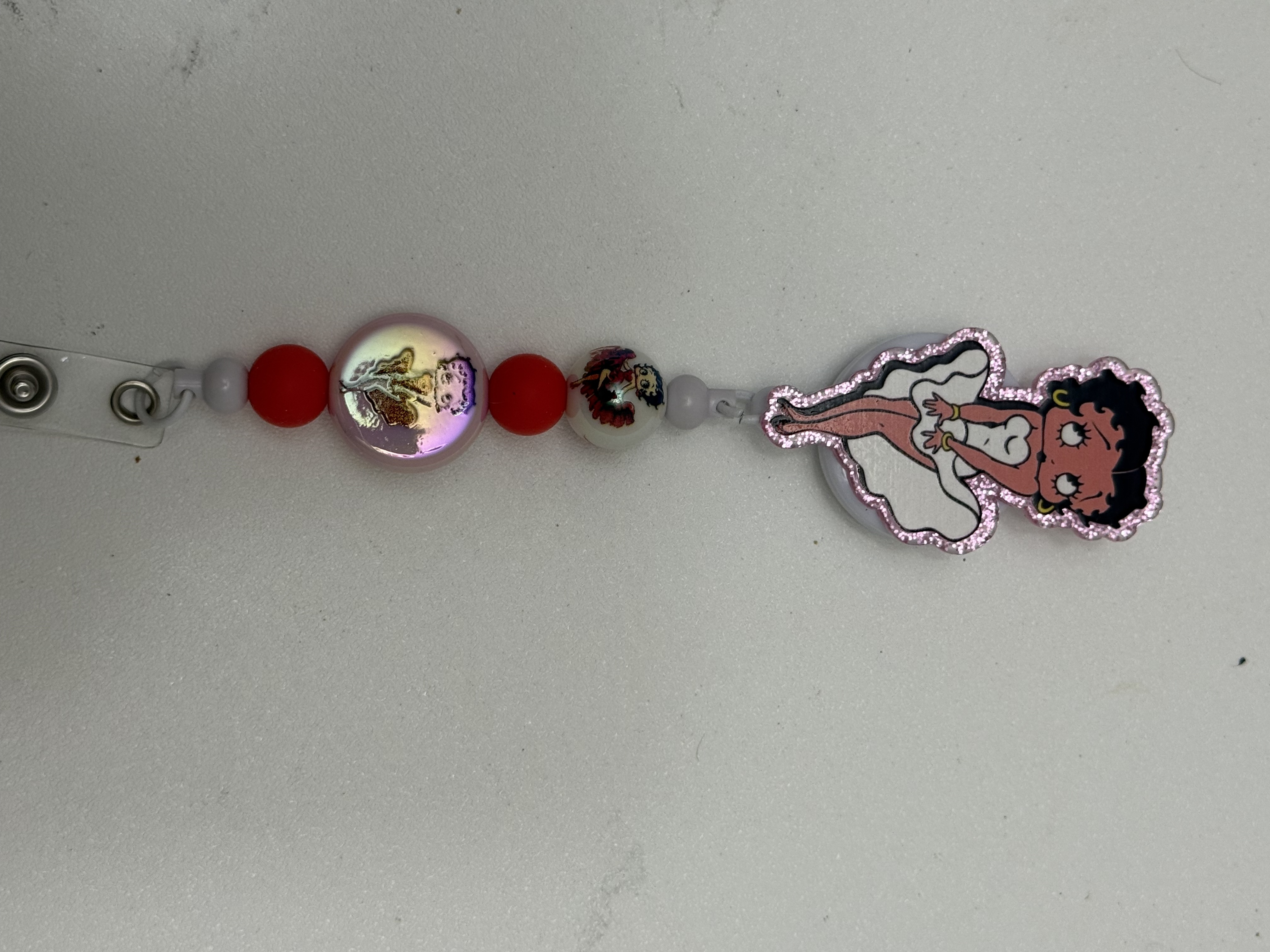 Retractable badge reel with pink glitter acrylic pin-up charm and iridescent red beads