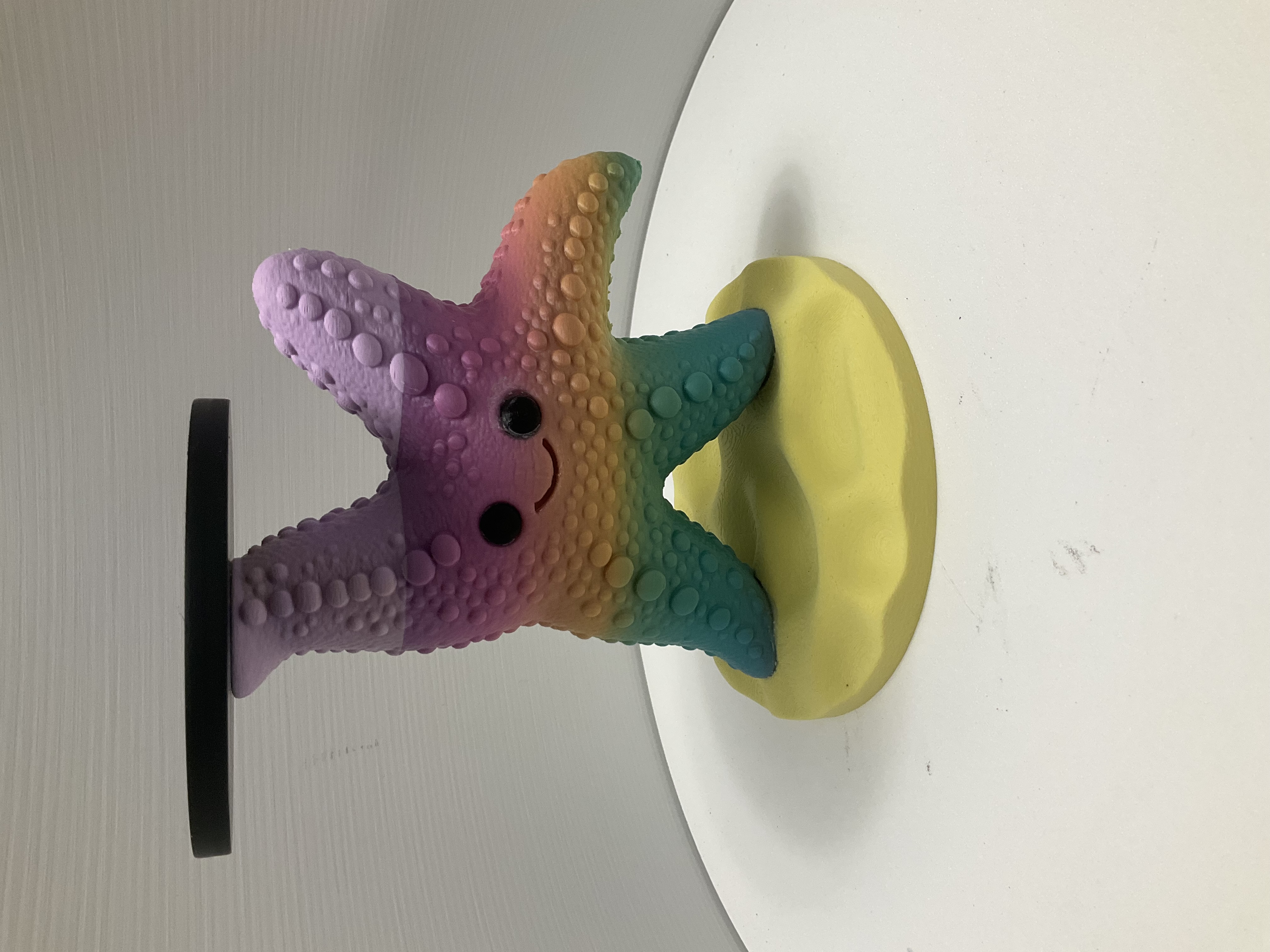 Smiling kawaii starfish candle holder with rainbow gradient and black disc platform