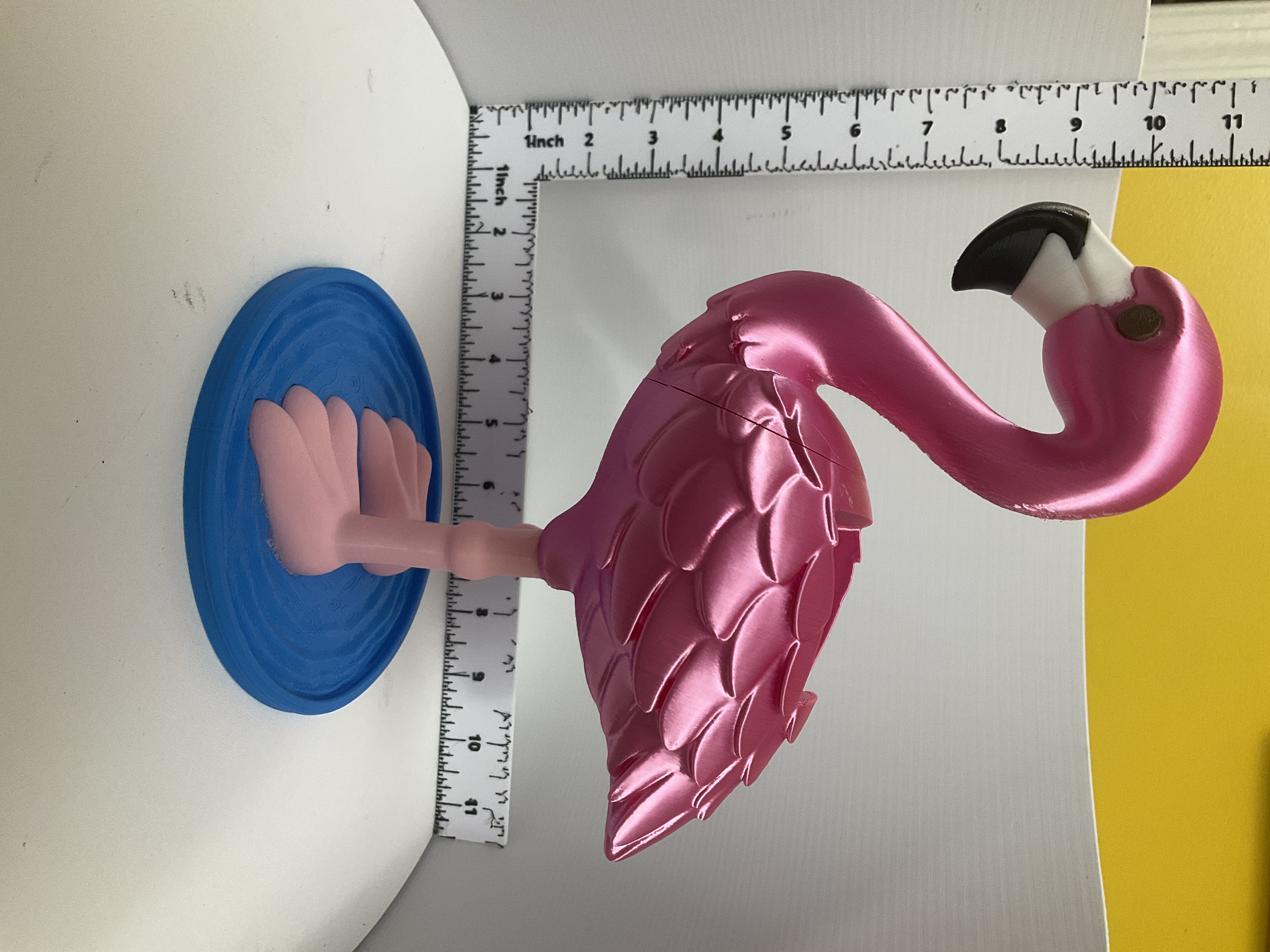 Side view of shimmery pink flamingo soap dispenser standing on blue rippled base