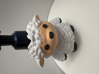 Close-up of a white woolly sheep-shaped soap dispenser with dark pump top