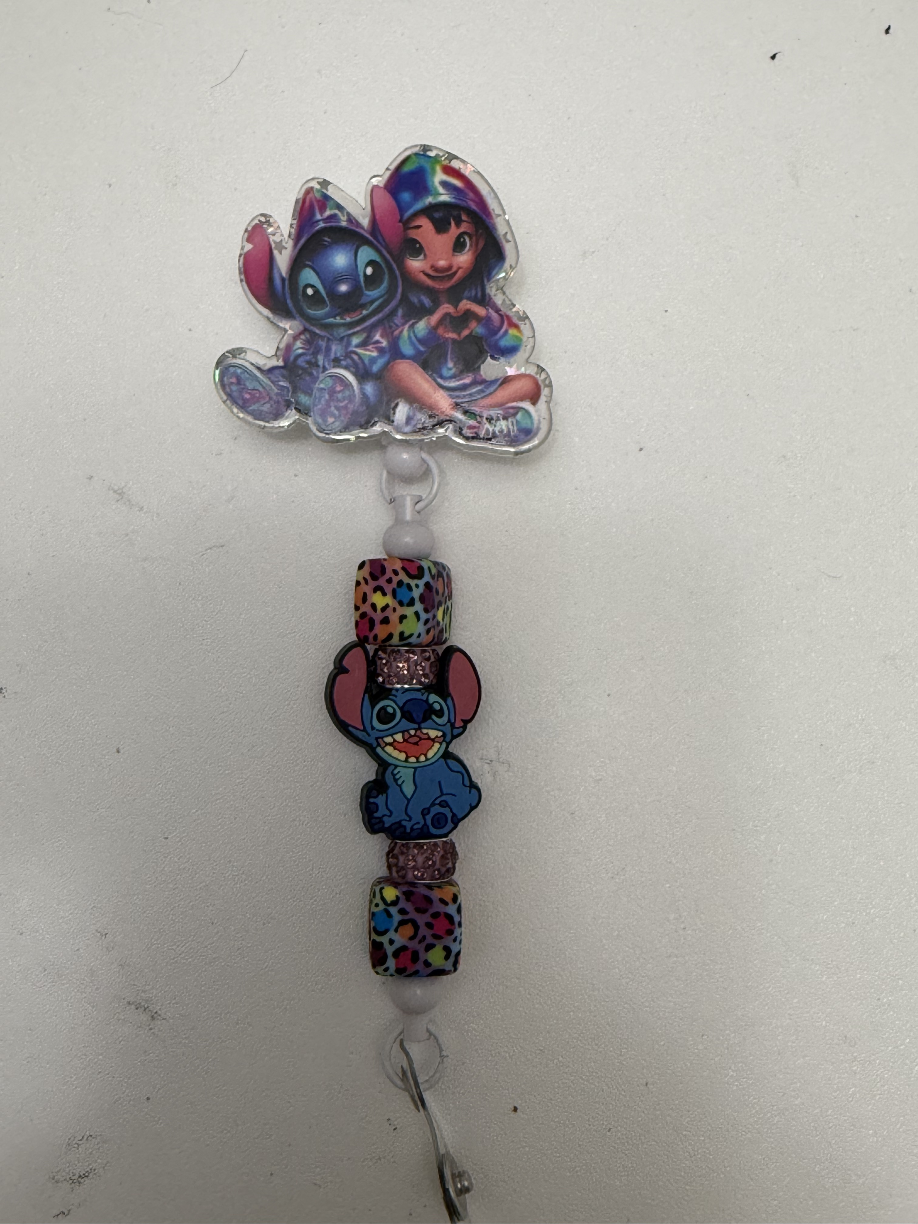 Retractable badge reel with tie-dye acrylic topper, leopard-print beads, and blue character charm