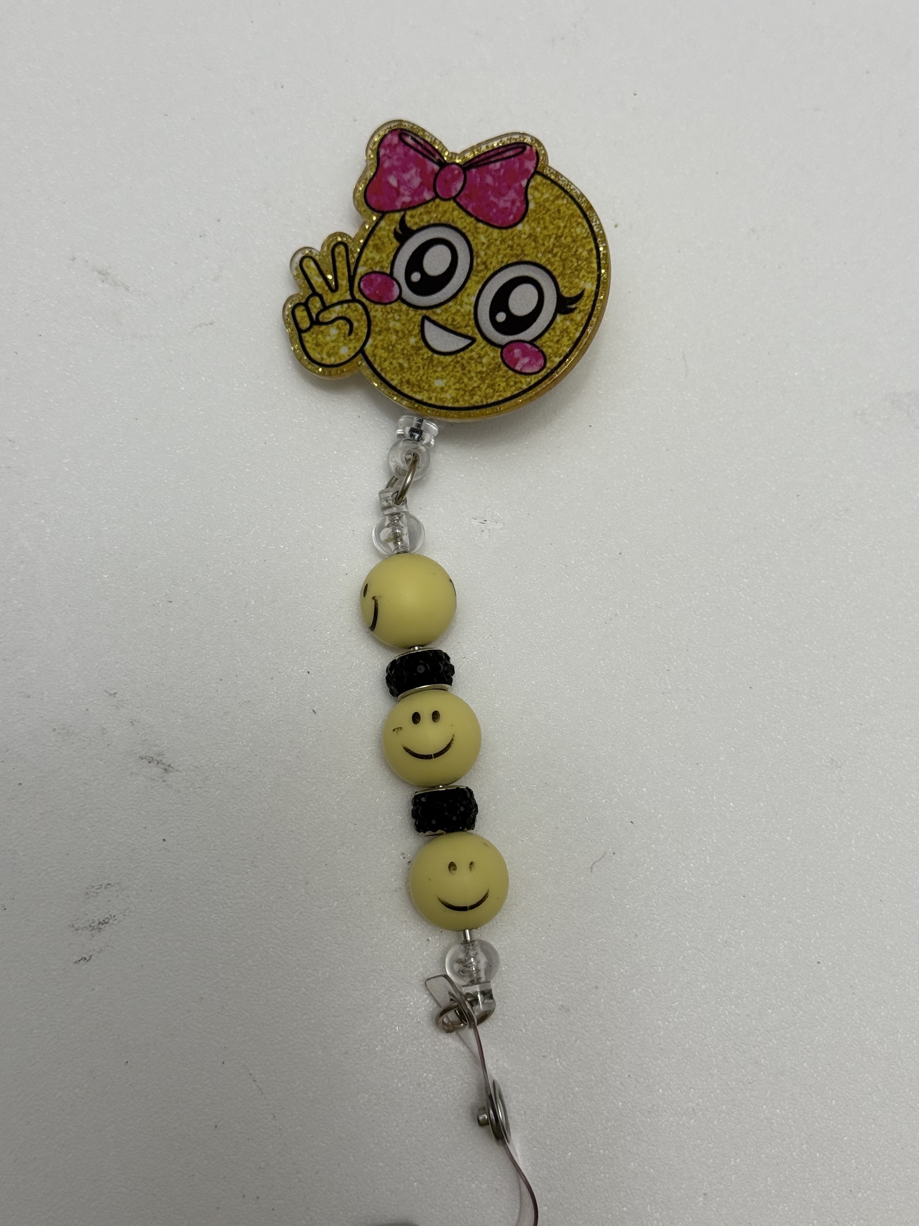 Gold glitter smiley face badge reel with pink bow and beaded yellow smiley charm strand