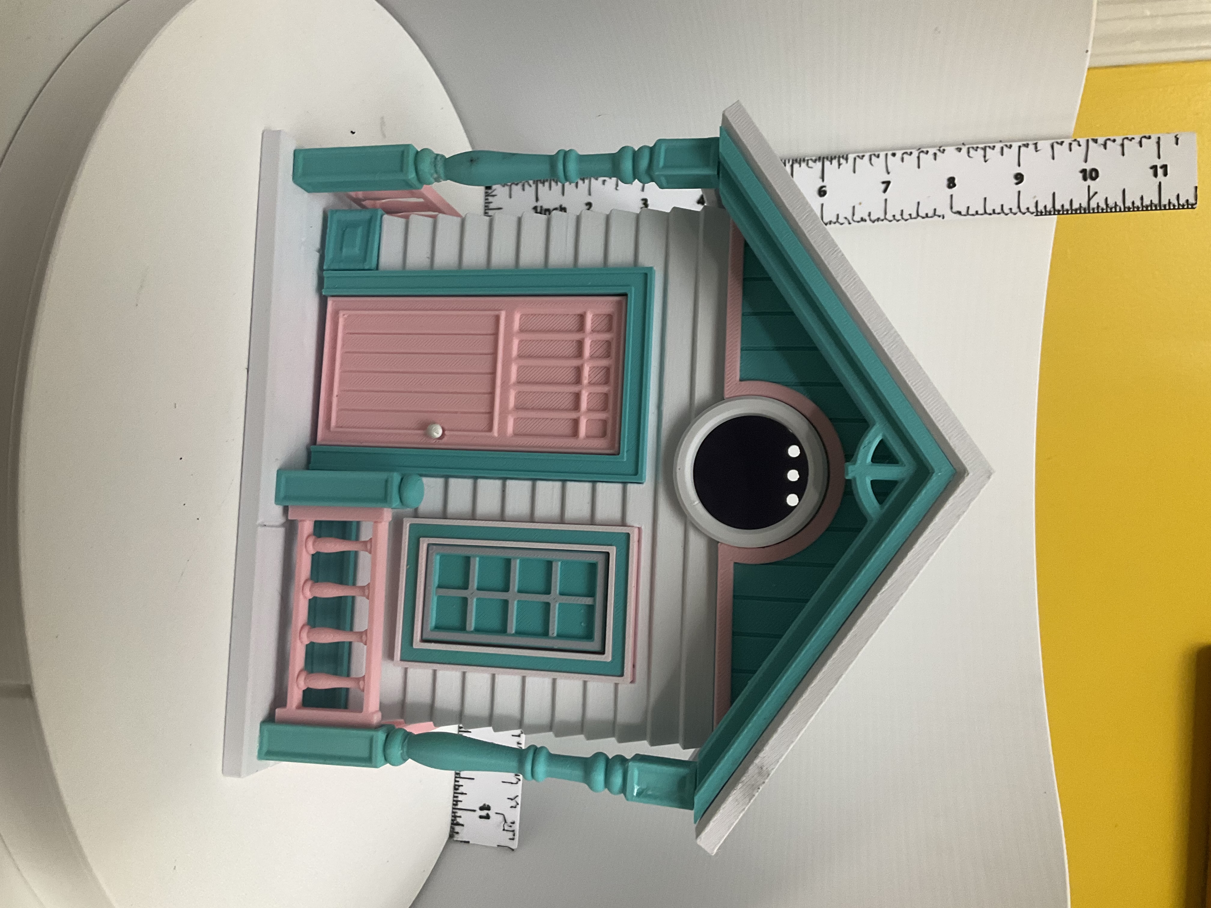 Front view of pastel birdhouse showing round entry hole pink door and teal gable