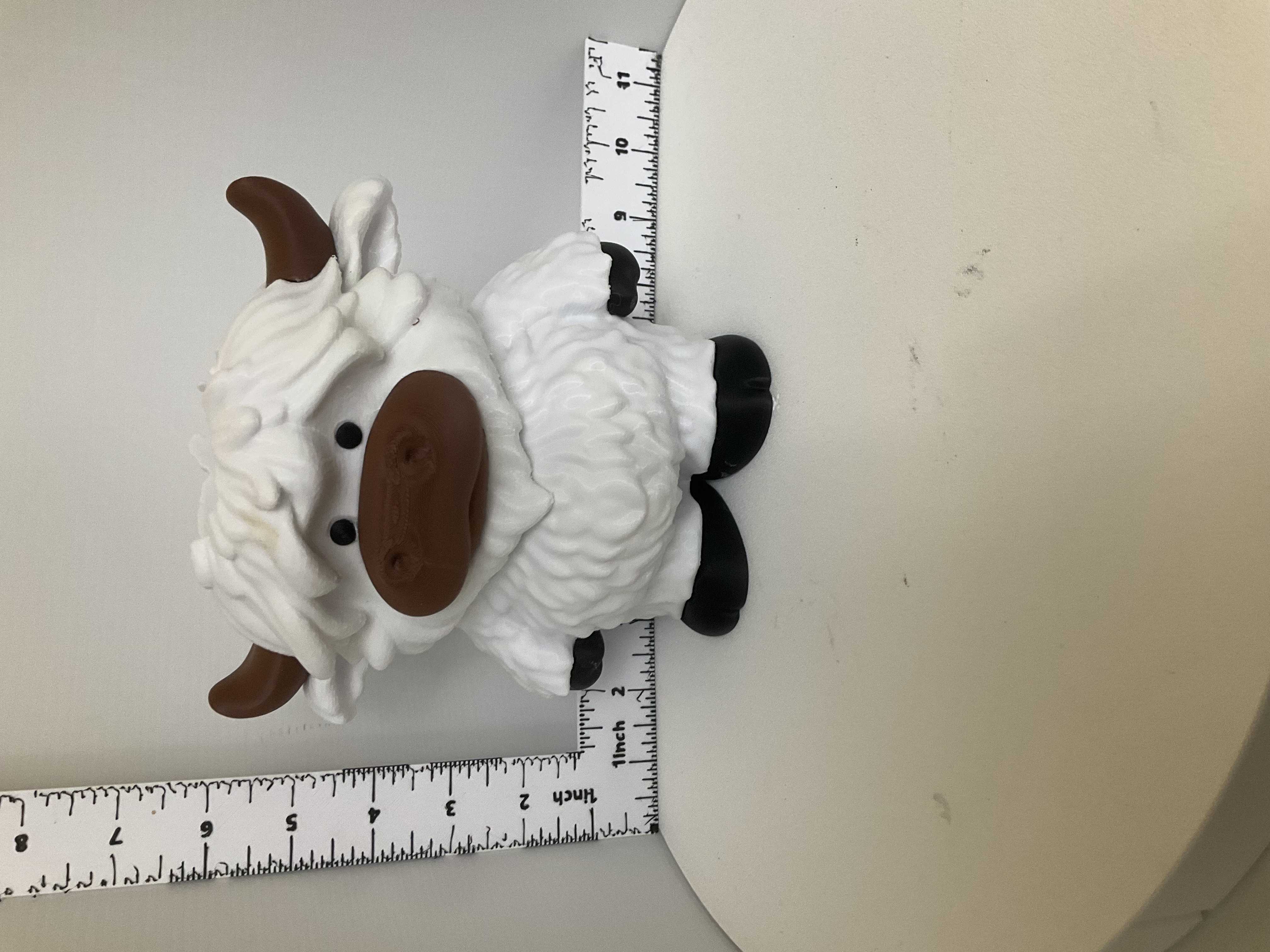 Chubby white highland cow soap dispenser holder with brown horns and black hooves shown next to ruler for scale