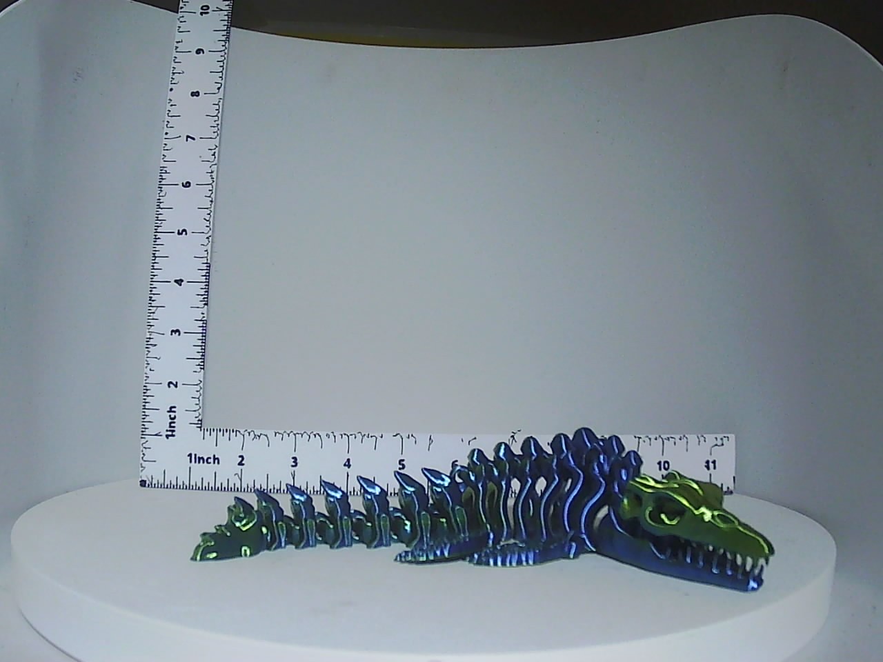Blue and green articulated skeleton dragon displayed next to a ruler showing approximately eleven inches in length