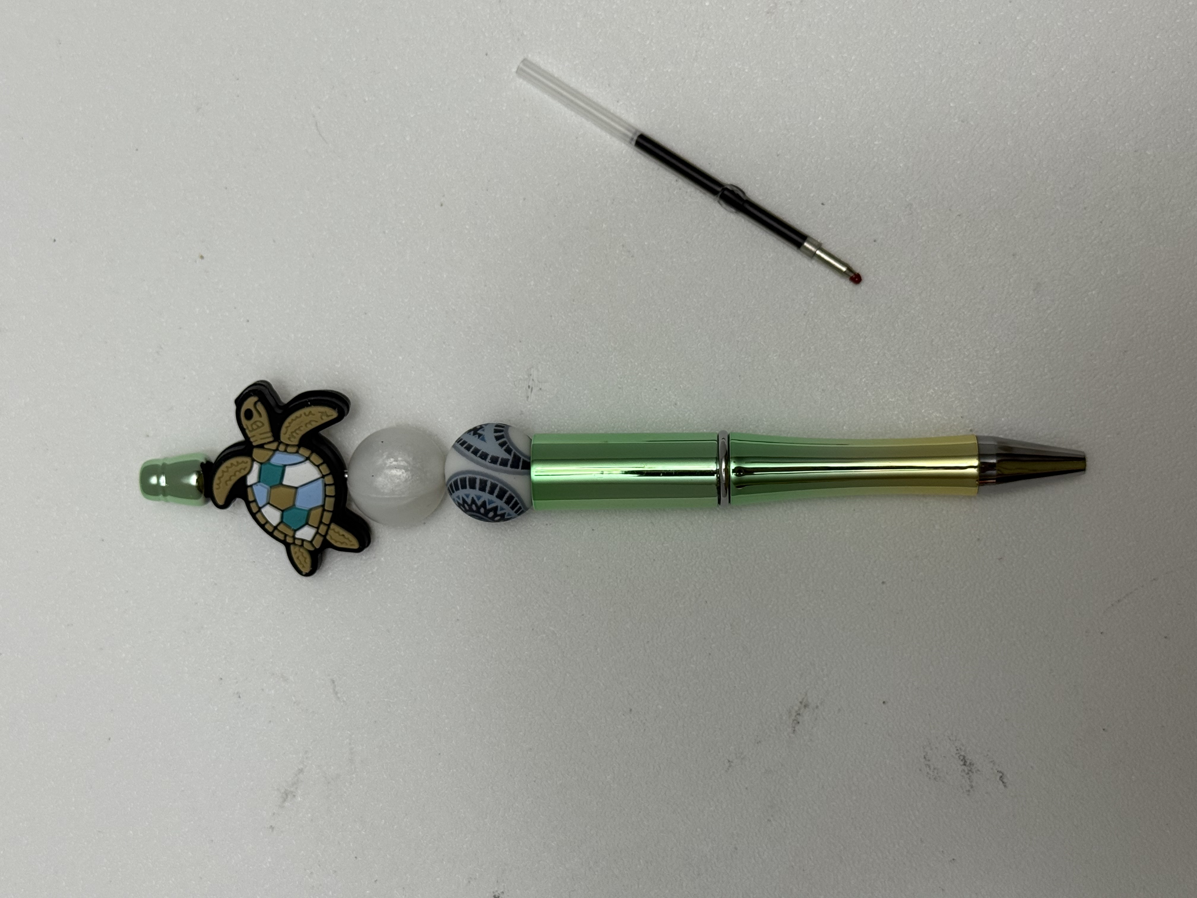 Green metallic ballpoint pen with mosaic sea turtle focal charm and mixed decorative beads