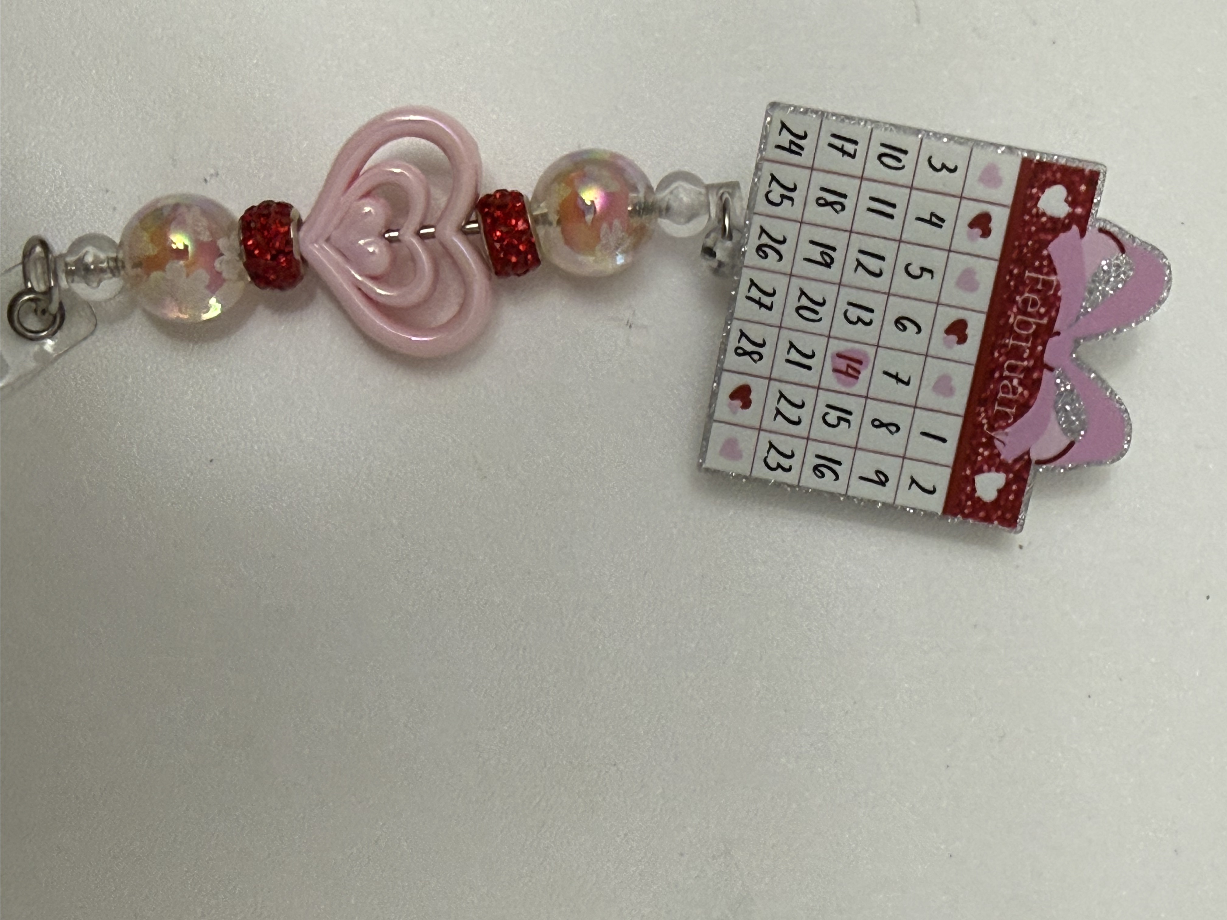 February calendar badge charm with pink heart, iridescent beads, and red rhinestone spacers