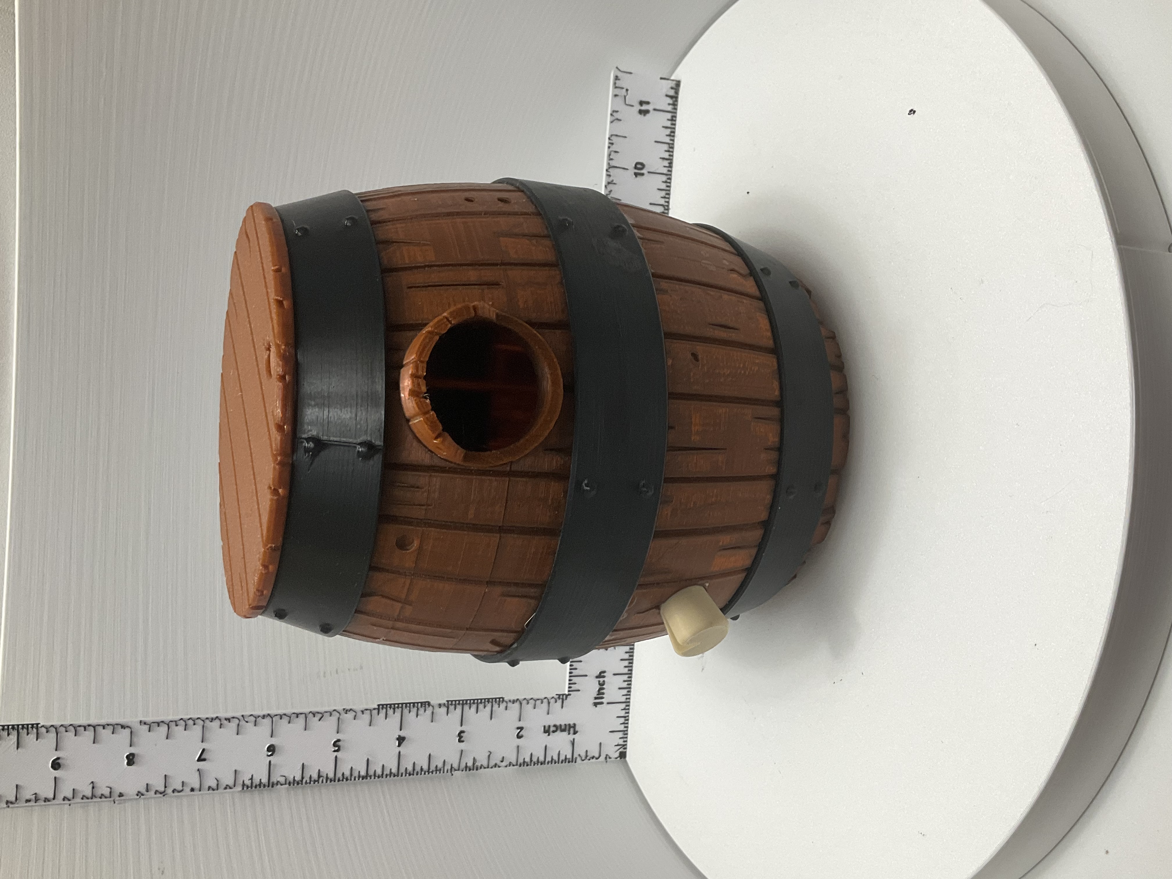 Barrel birdhouse shown next to ruler for scale, flat lid and round entry hole visible
