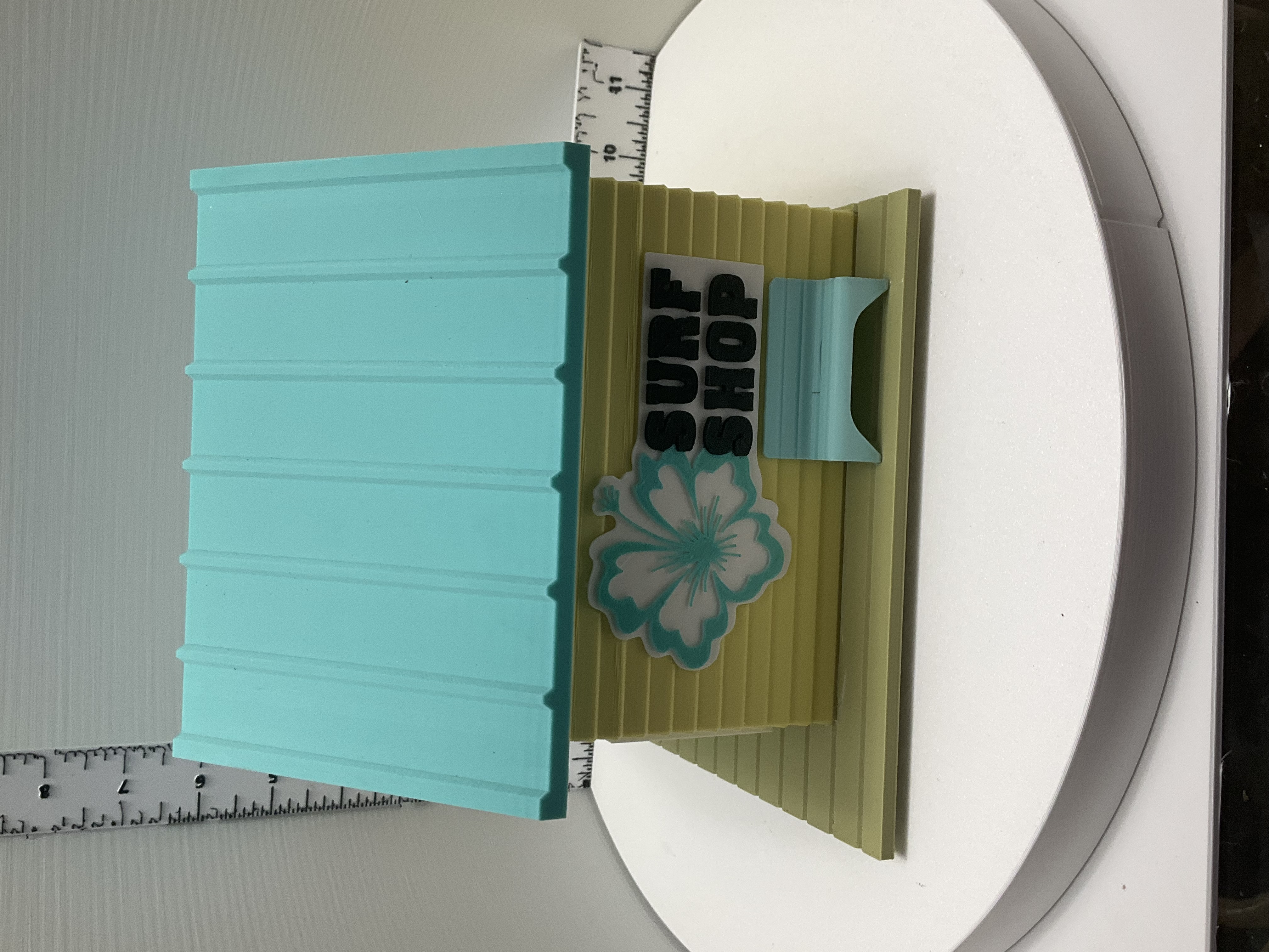 Back of surf shop birdhouse showing hibiscus sign, entry hole, and teal perch