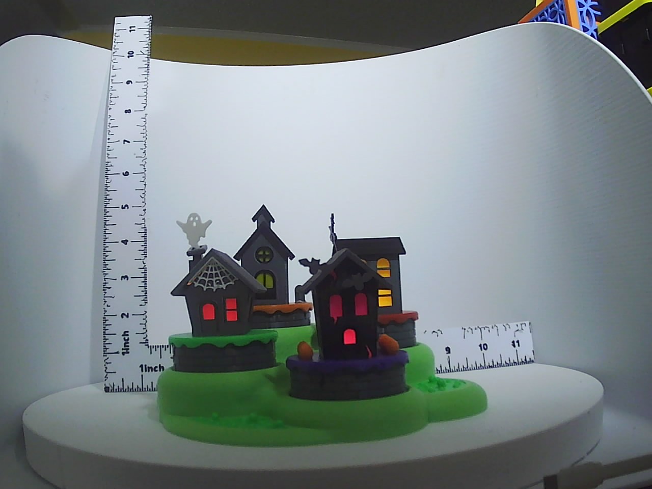 Three dark haunted houses glowing red and amber on green bases with ghost and bat details