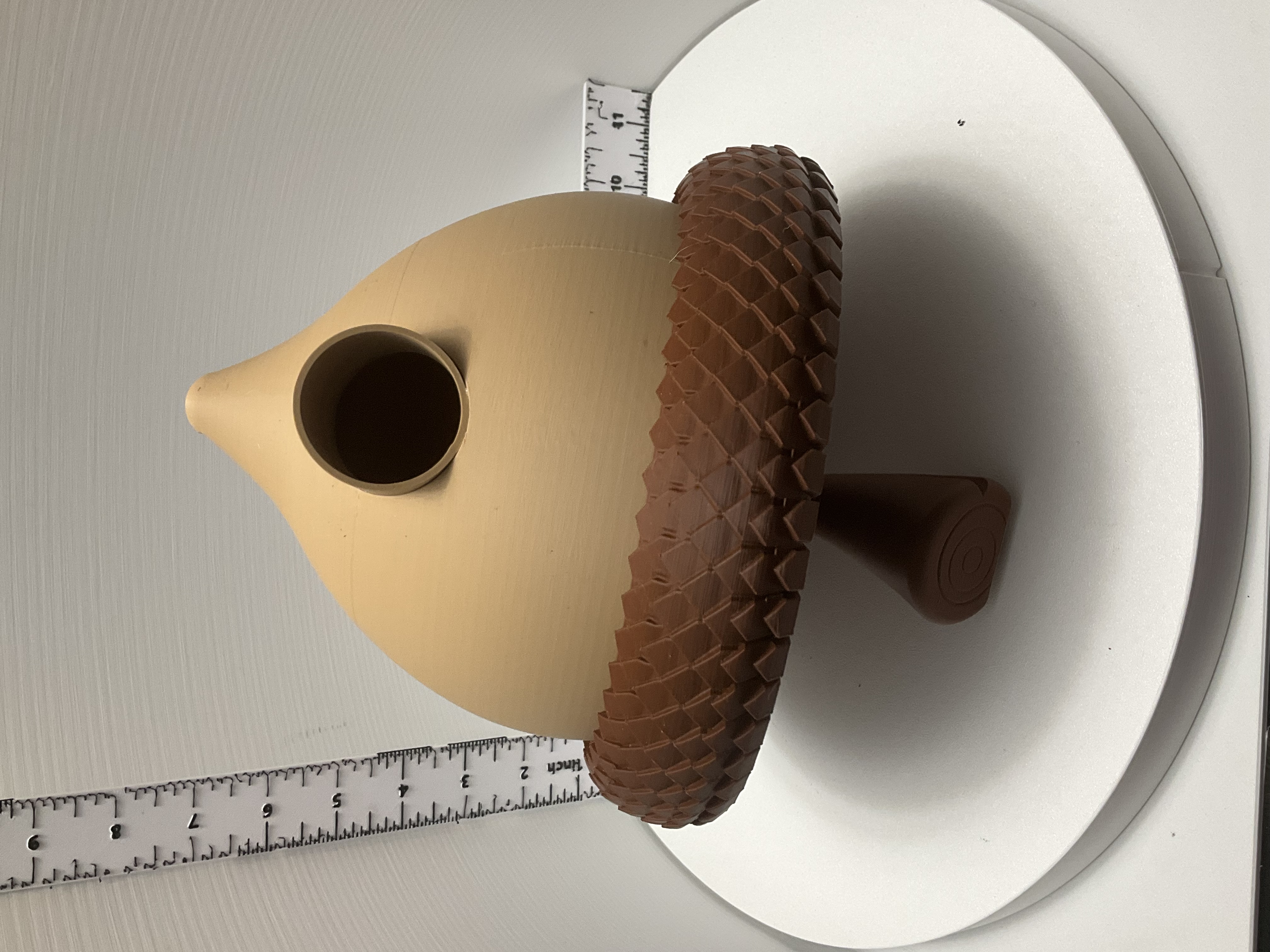 Tan and brown 3D printed acorn birdhouse with scalloped cap and stem base displayed on white turntable