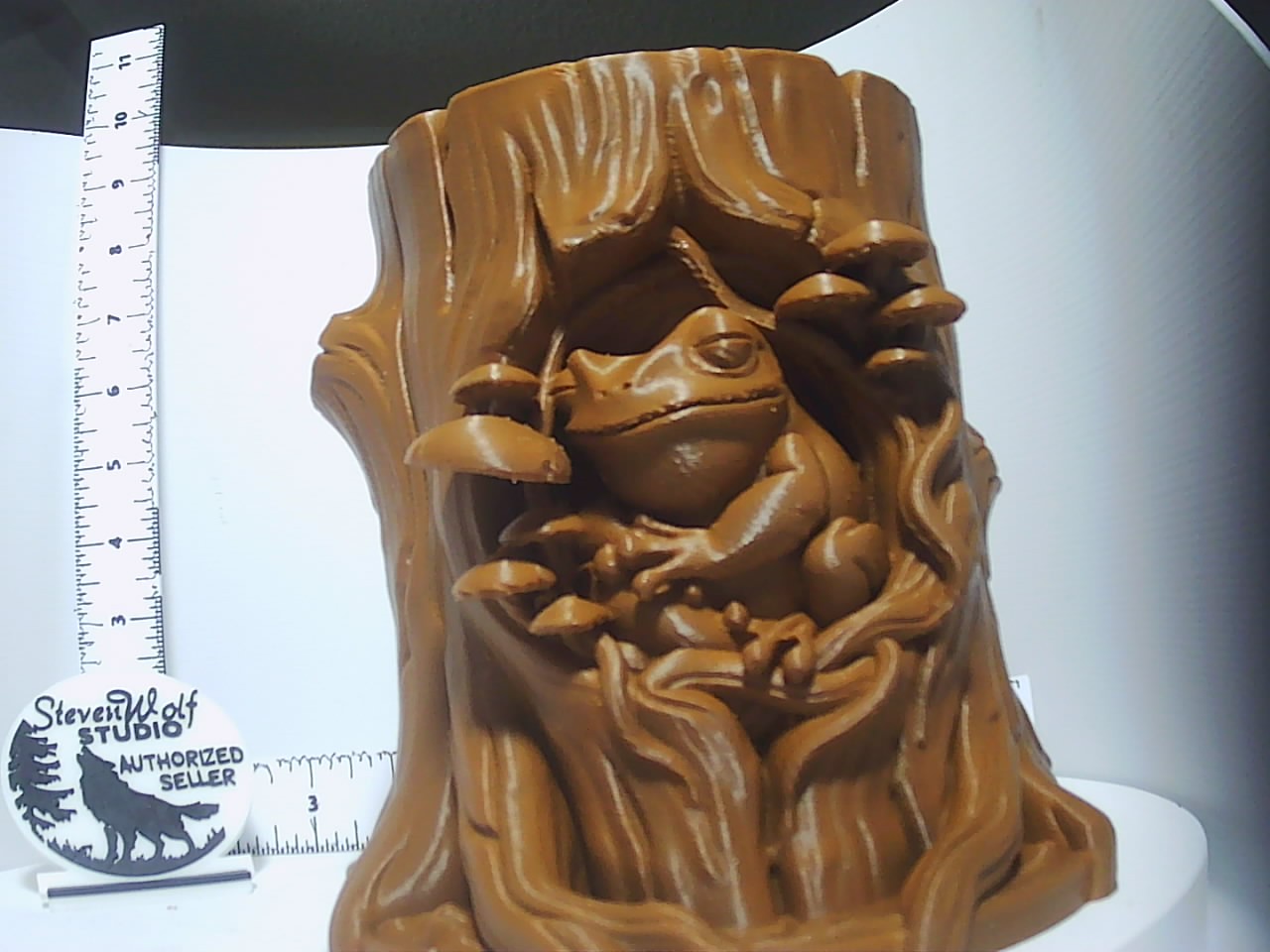 Warm brown 3D-printed tree stump planter with frog and mushrooms carved in relief