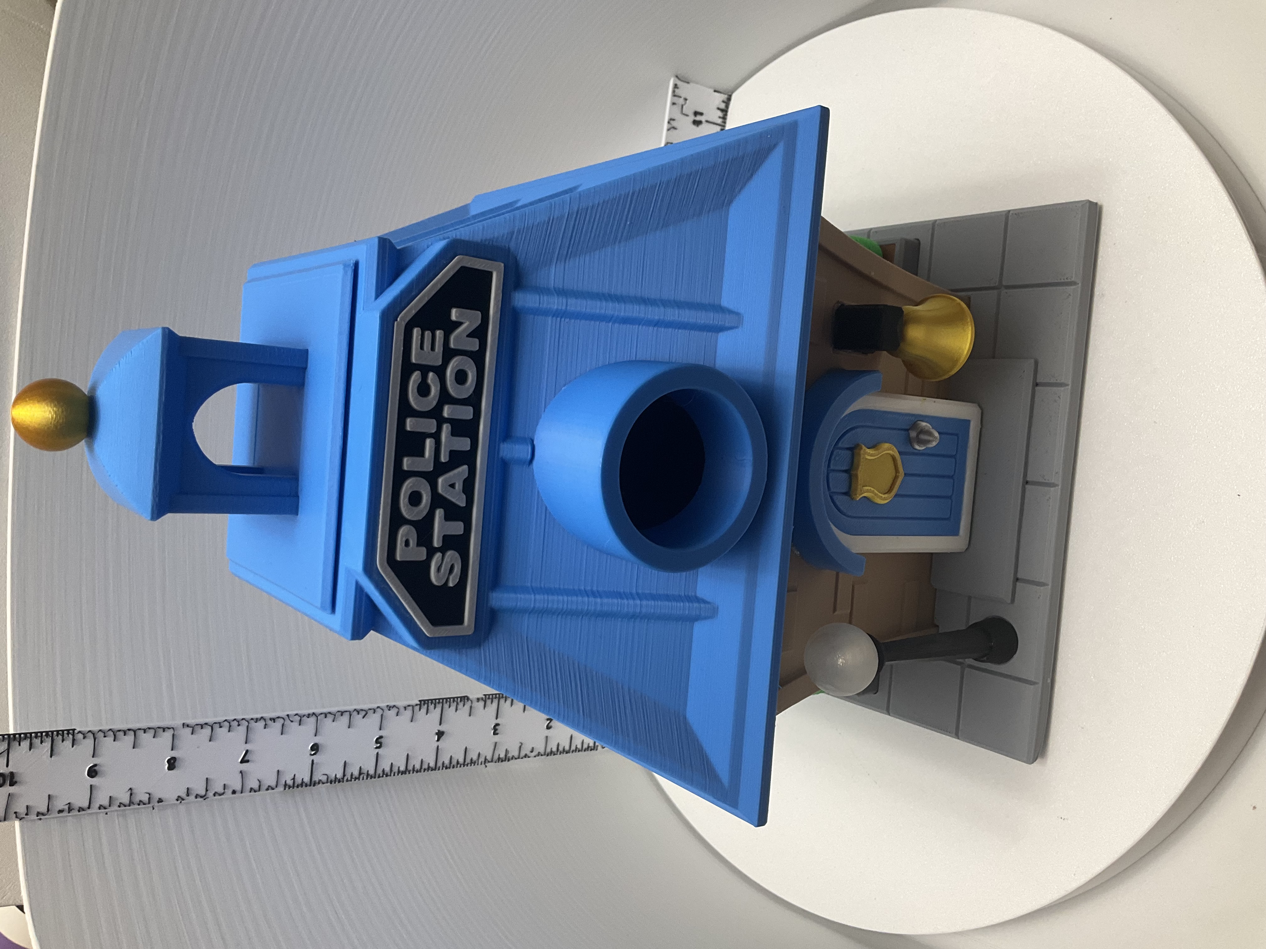 Angled front view showing cupola with gold finial atop blue police station birdhouse