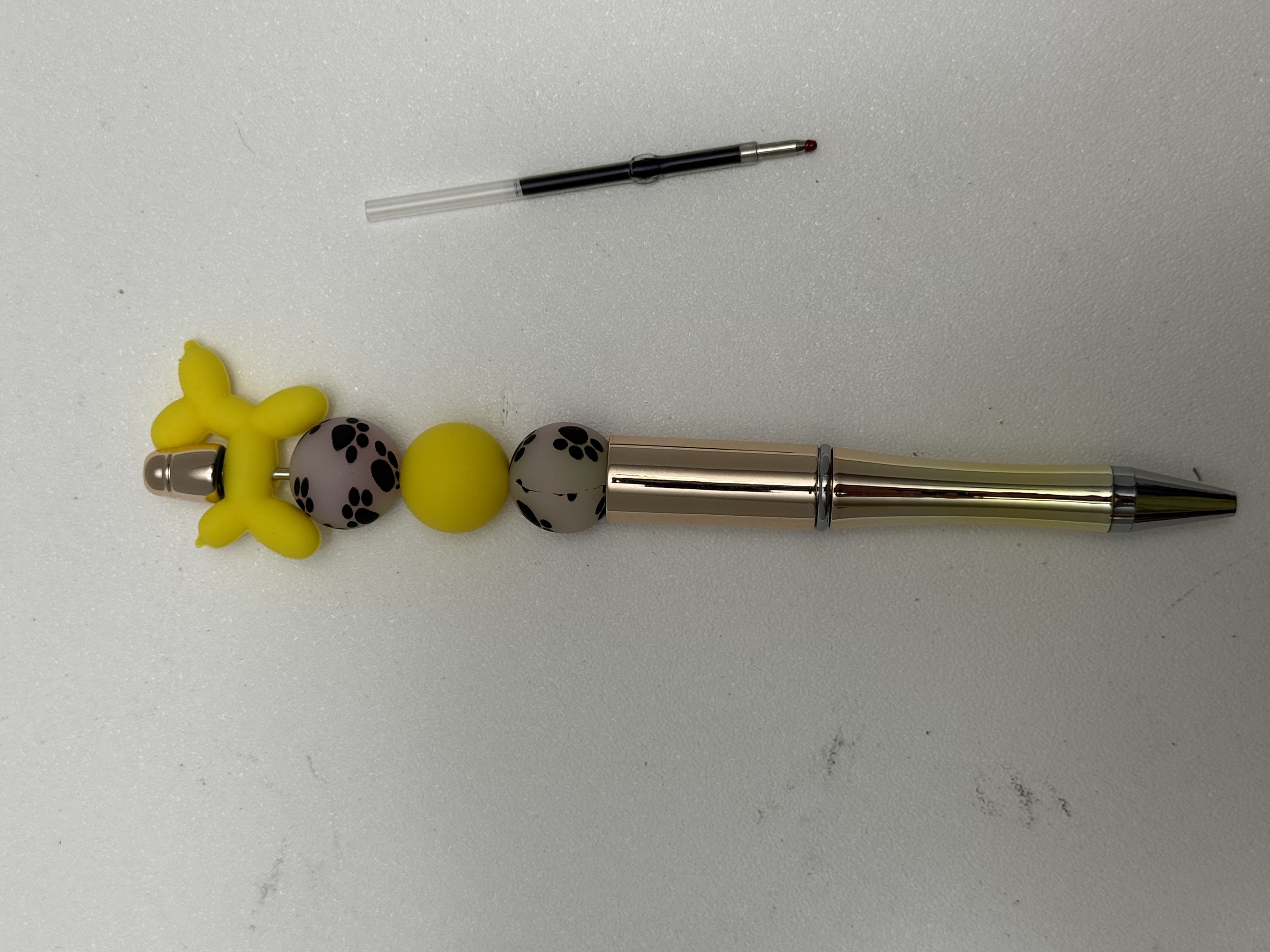 Yellow balloon-dog beaded ballpoint pen with paw-print beads and spare ink refill