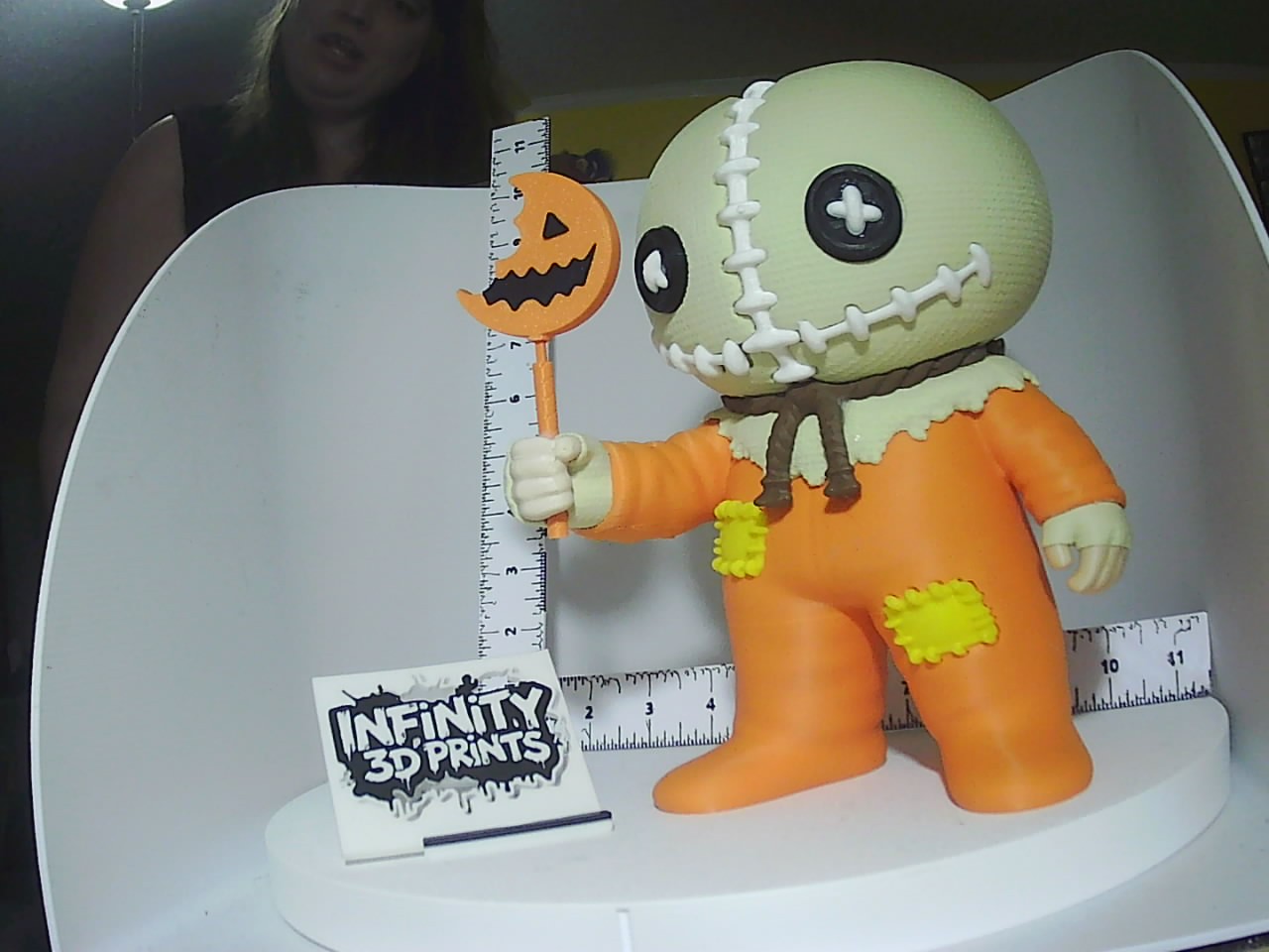 3D printed Halloween ragdoll figure with button eyes, orange jumpsuit, stitched burlap head, and jack-o-lantern staff
