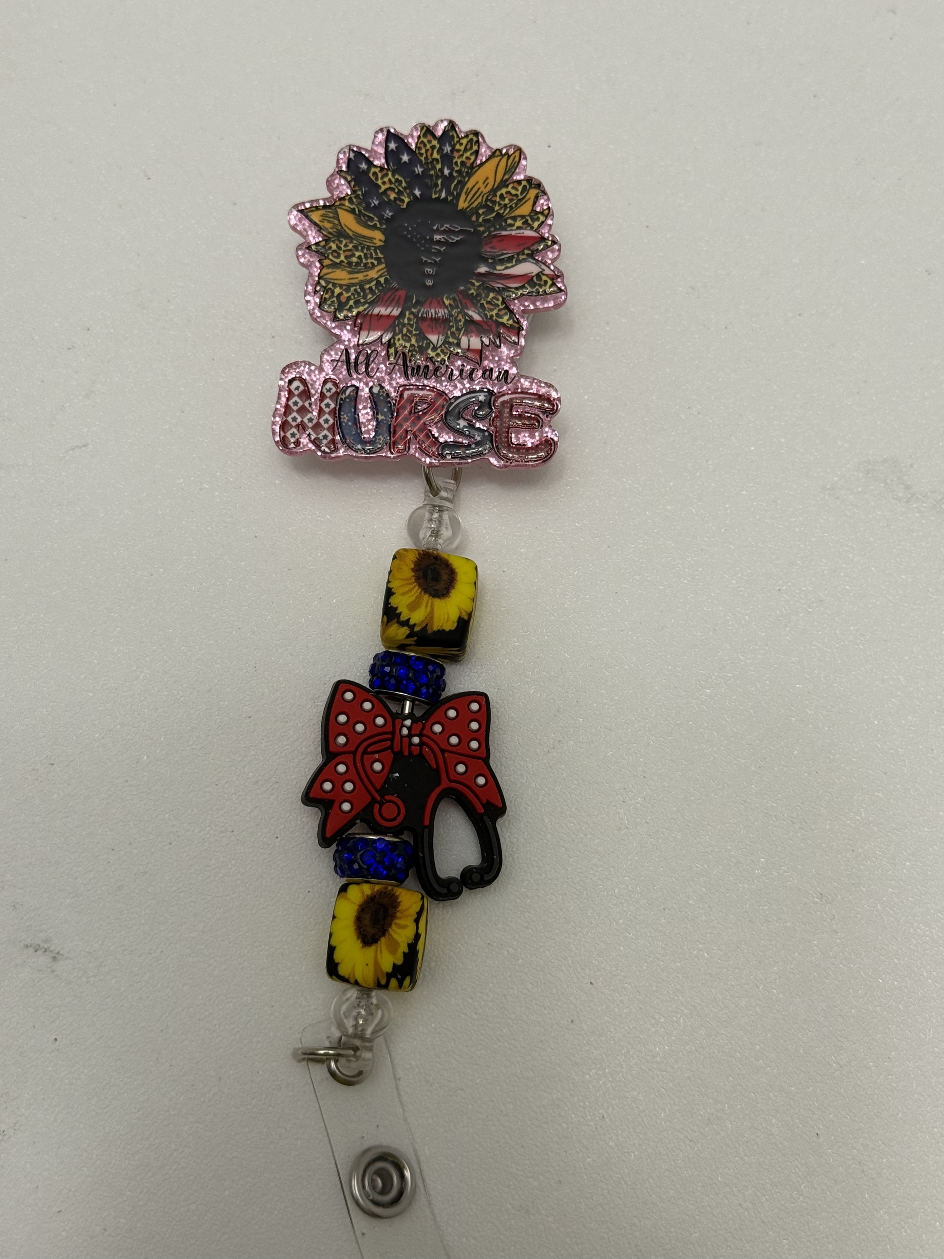Retractable nurse badge reel with sunflower topper, rhinestone beads, and red bow stethoscope charm