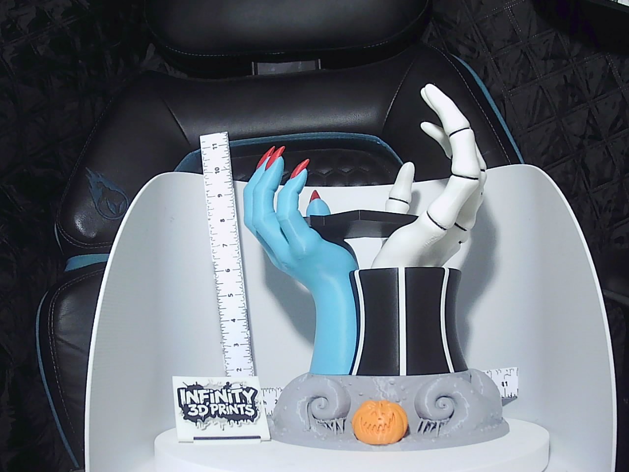Front view of blue and white skeleton hands rising from grey swirl base with orange jack-o-lantern