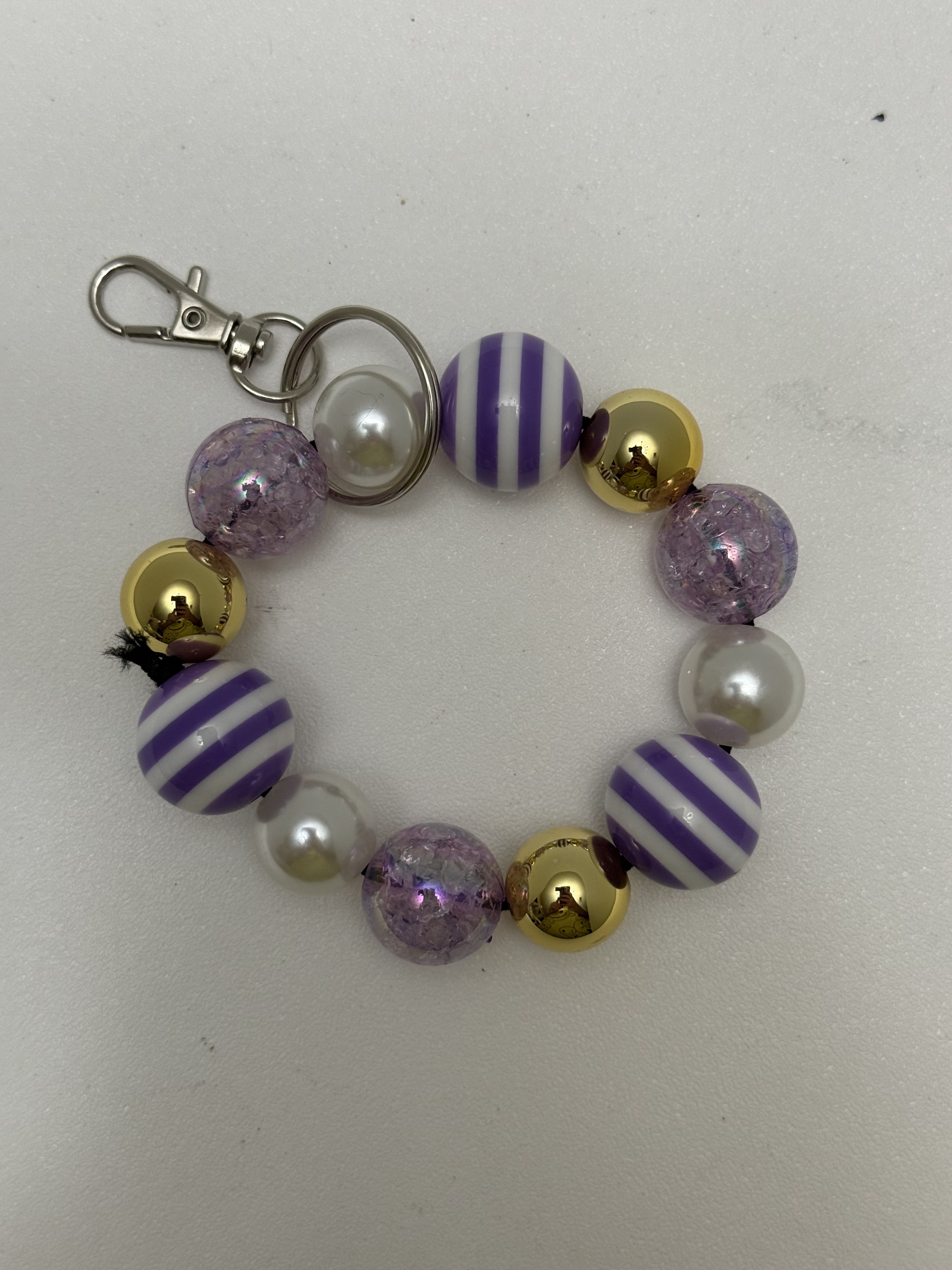 Circular chunky bead keychain with purple stripe, lavender crackle, pearl, and gold beads on silver clasp