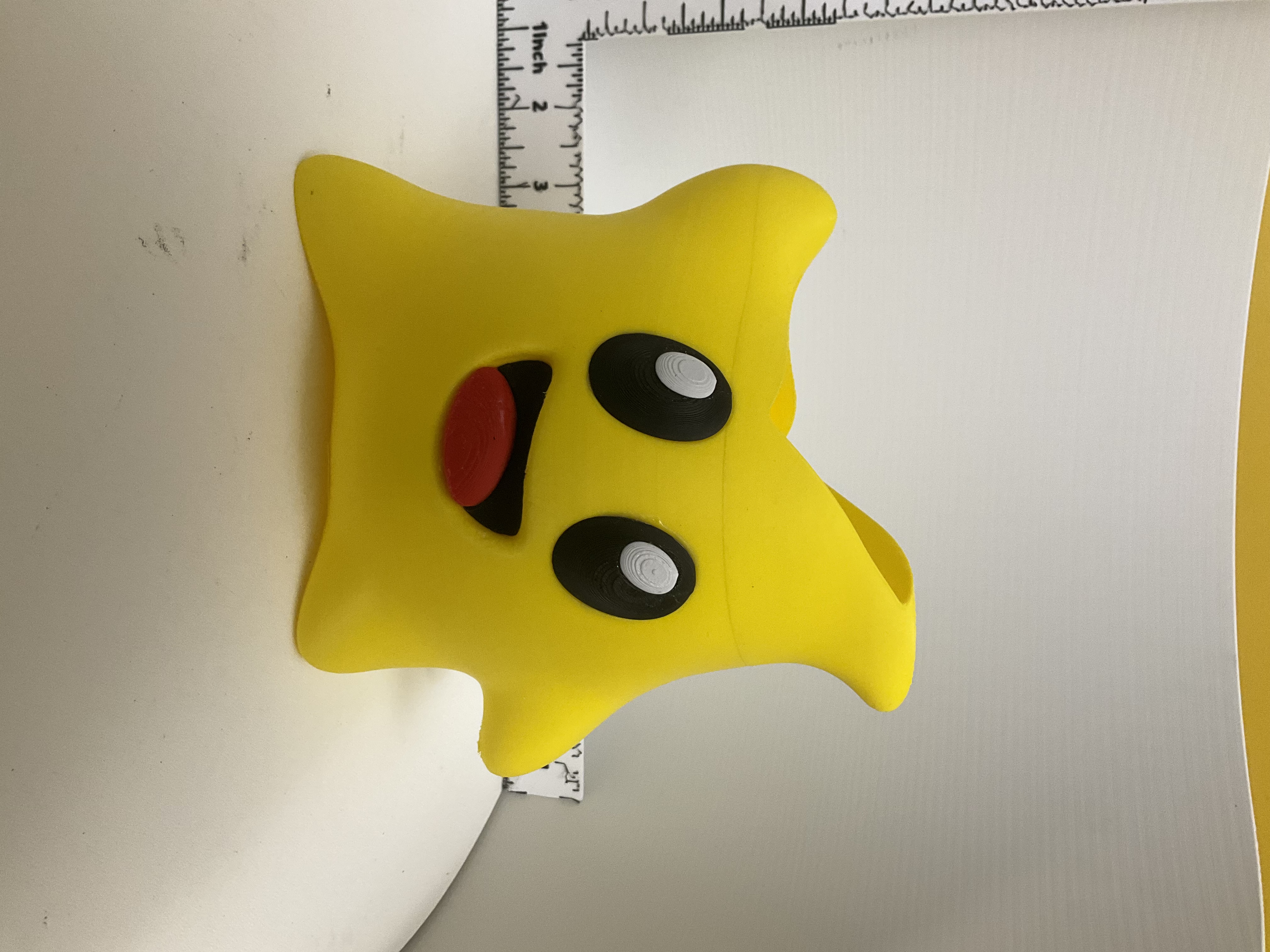 Front view of yellow star-shaped holder with smiling face, black eyes, and red tongue