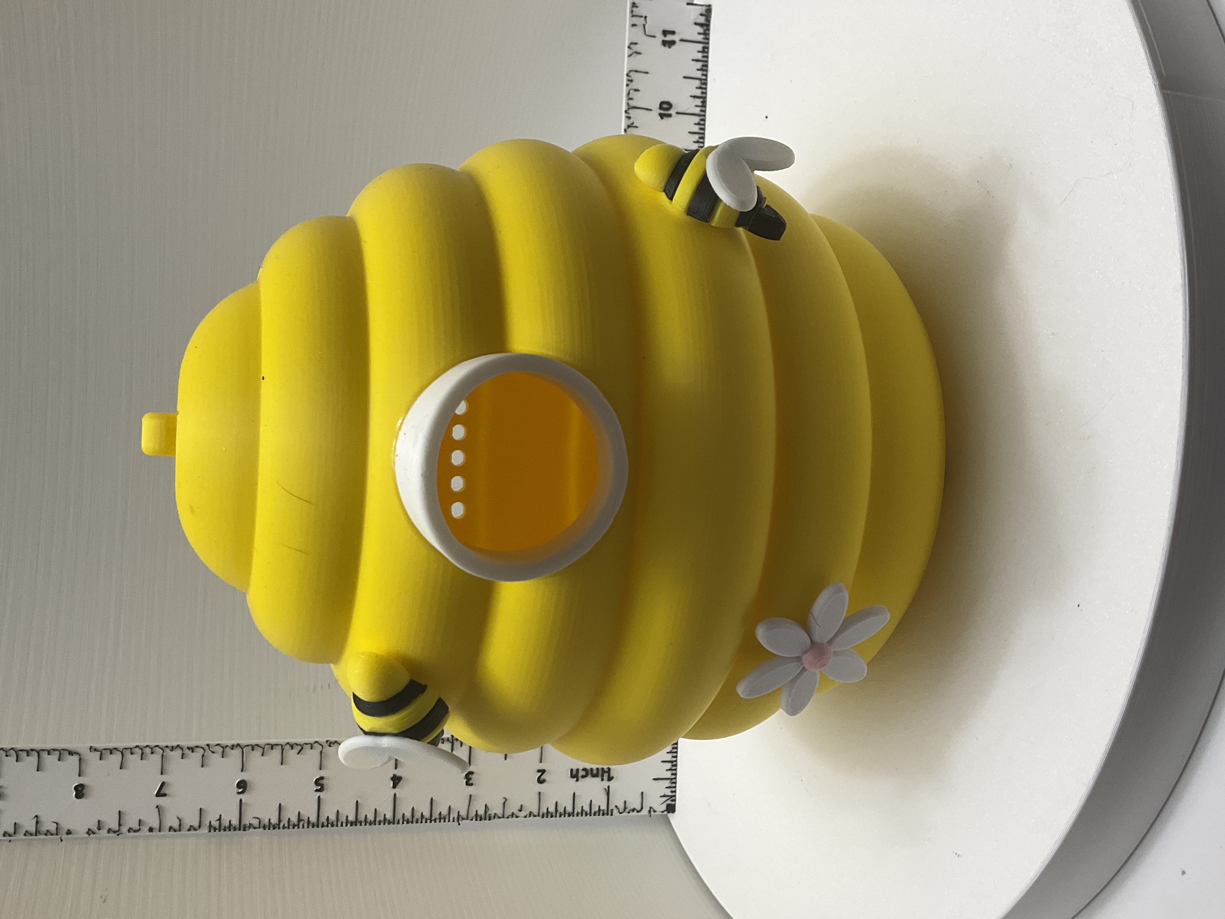 Yellow ridged beehive figurine with two striped bees, white daisy, and amber circular portal